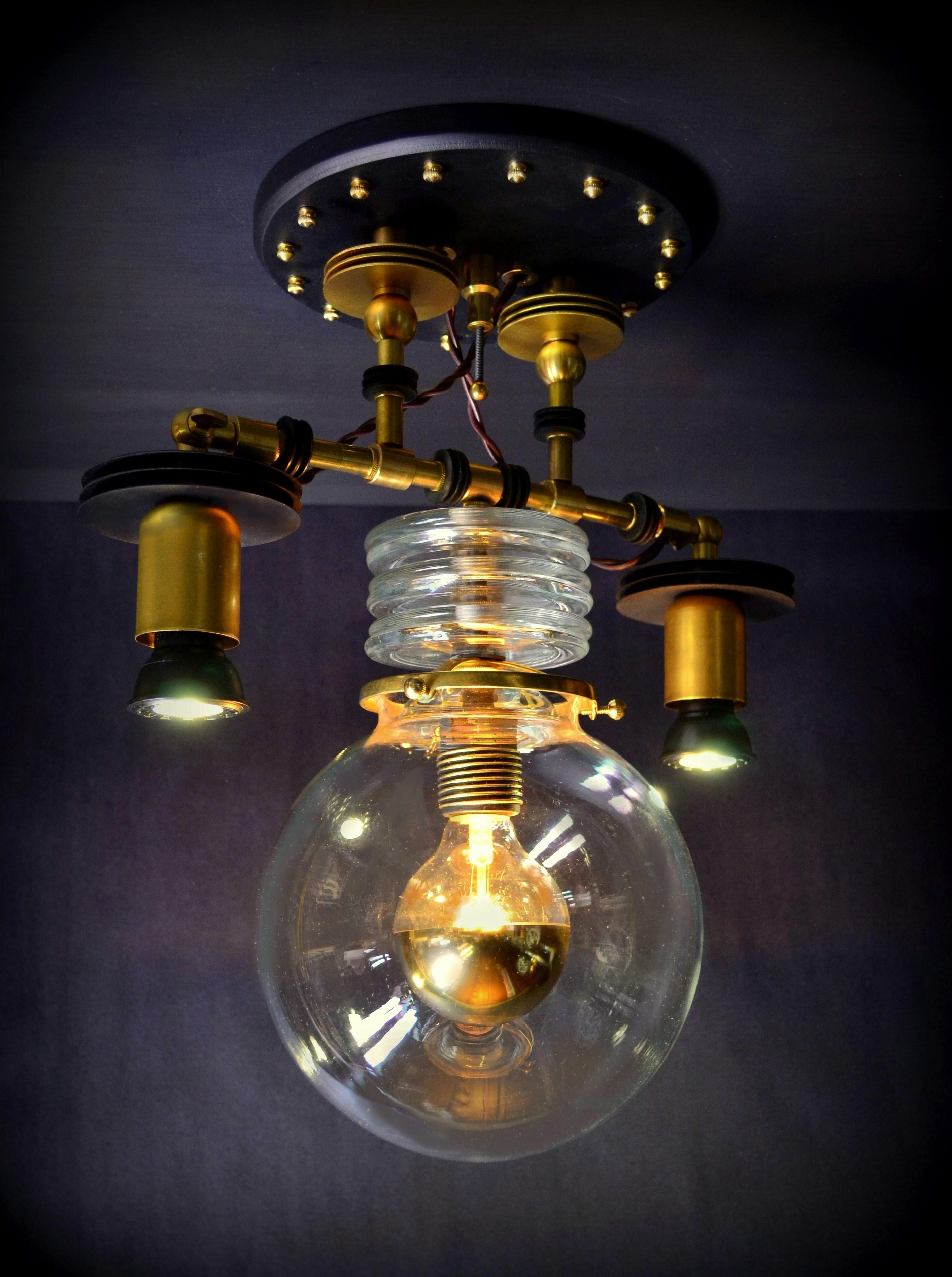 Designed and built by Steampunk master, Art Donovan, the Tesla pendant light features the illuminated center globe with the addition of customized LED spot lights, left and right. High Industrial style. Steampunk with a minimalist pallet in black