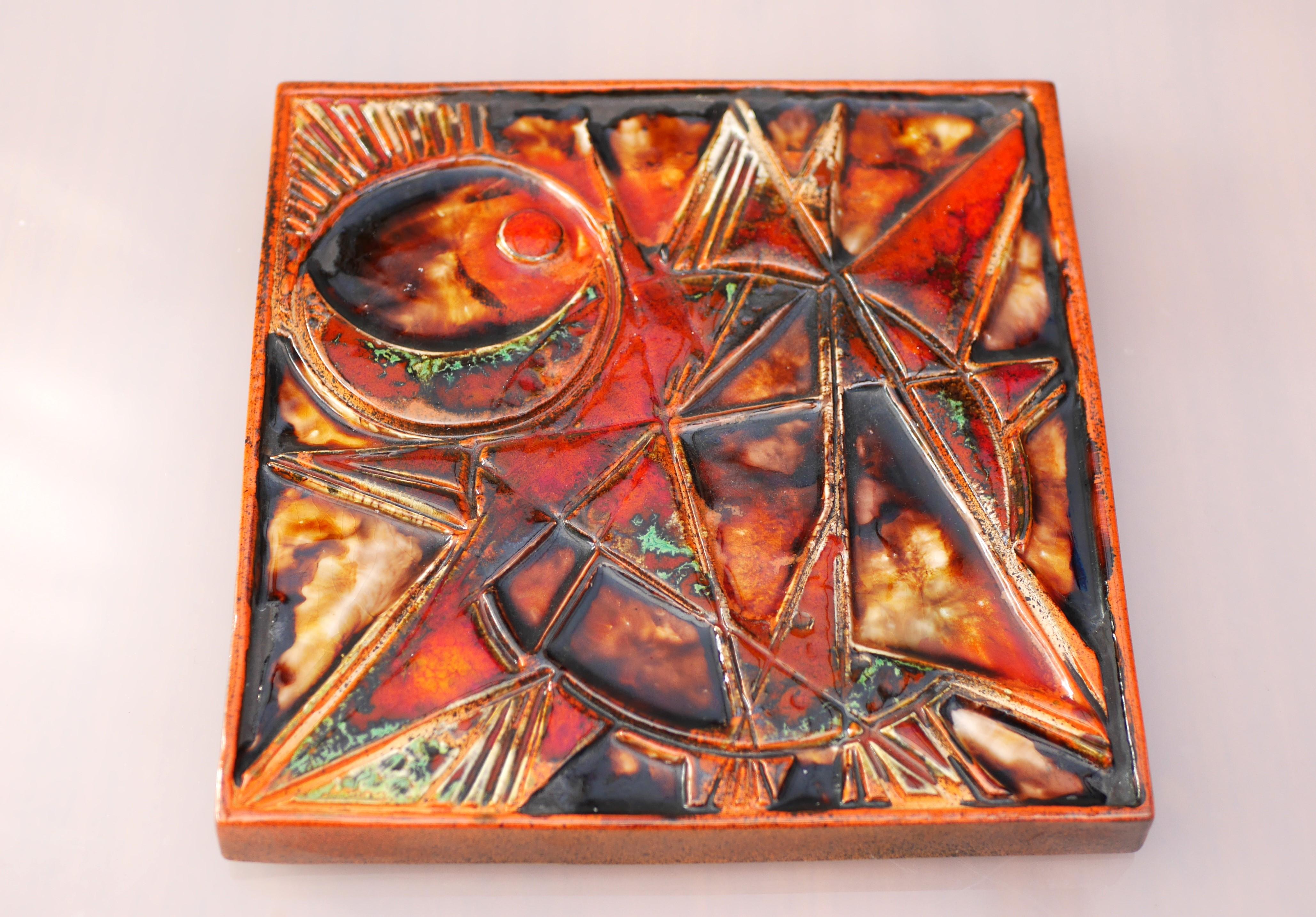 A unique and rather large ceramic wall plaque with an abstract pattern of a star and amazing colors from Tilgmans, Sweden. The amazing glazing has a rust orange or red base with some vibrant red, green and darker details. This is a piece of art,