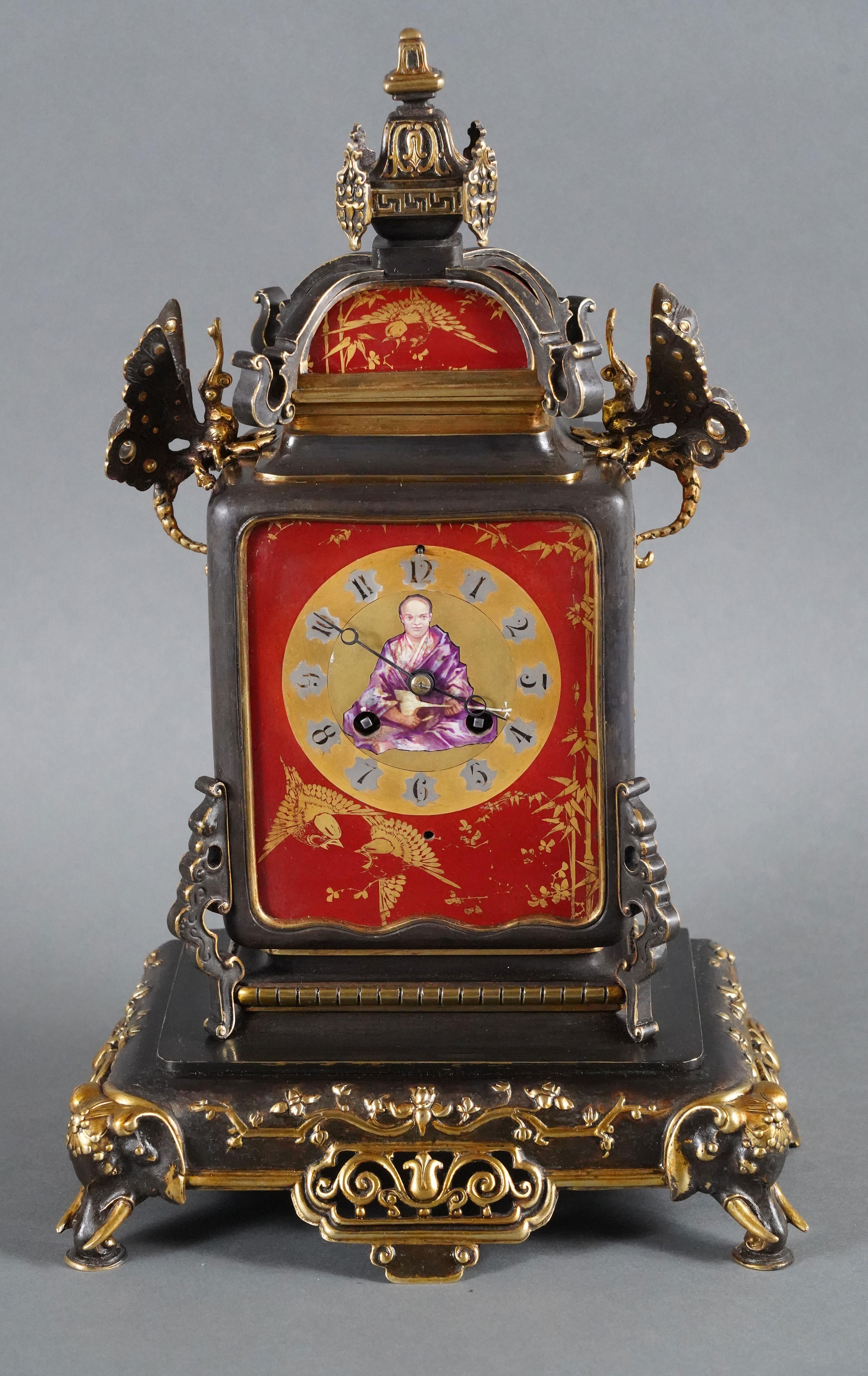 Amusing bronze with double patina and porcelain clock in the shape of a covered jar.
This clock, with a dial with Arabic numerals decorated in its center with a seated lute player, is topped with a lantern and framed by two butterflies with