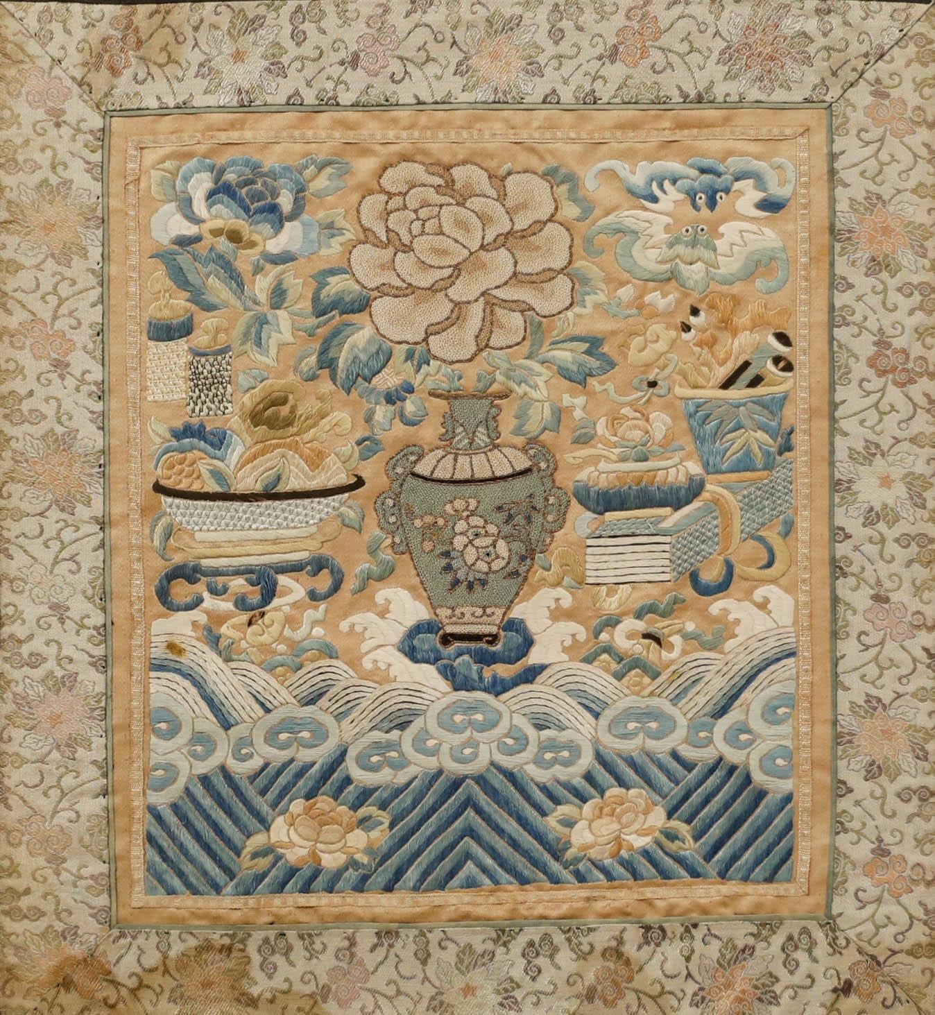 A delicate 19th century Chinese silk embroidery panel, depicting a vase of flowers floating overclouds and waves within an embroidered foliateborder. Framed behind glass. On silk. 