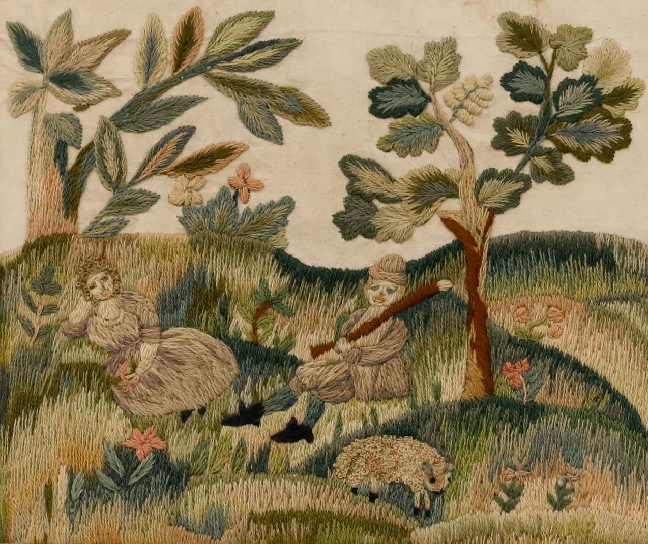 A delightful 18th-century woolwork depicting a couple leisurely resting in a blooming meadow beneath lush, leafy trees. The artist has expertly blended threads of green and pink to create this charming scene, rich with character. Unsigned. Smartly