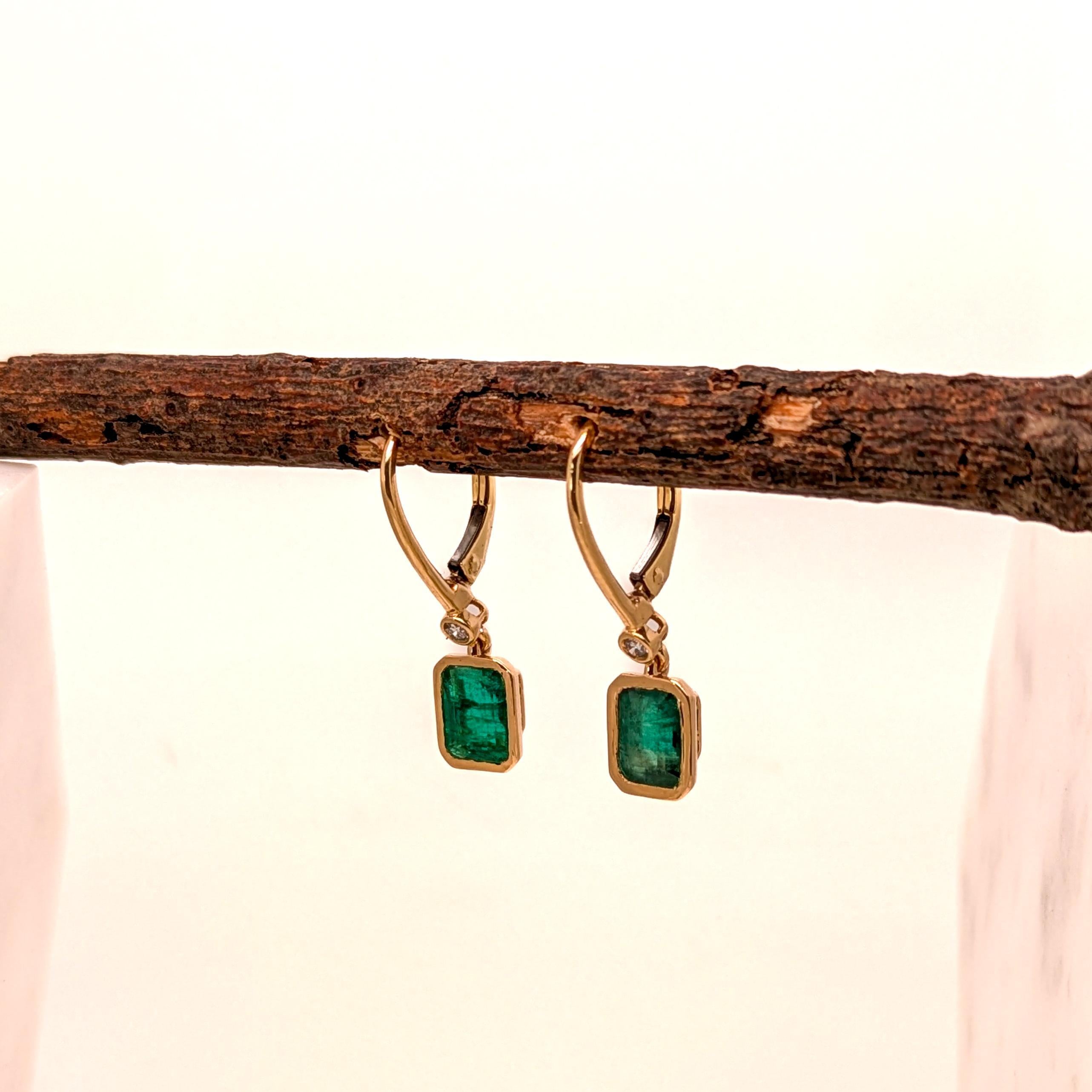 14K yellow gold hoop earrings feature a refined design with 2.35 carats of diamonds and striking emerald-cut emeralds. The emeralds measure 7x5mm each, adding a bold pop of green to the jewelry. Set in high-quality yellow gold, these earrings offer