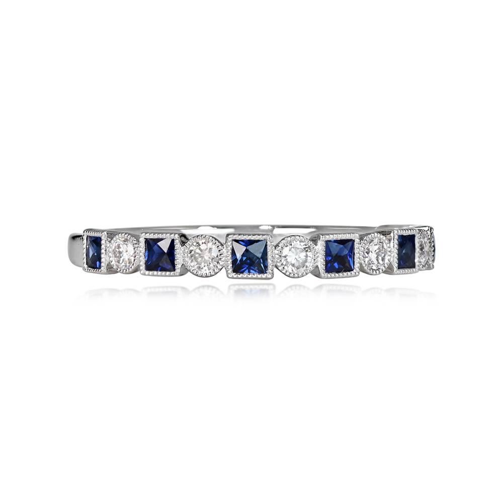 A beautiful half-eternity band with 0.12 carats of round brilliant cut diamonds and 0.21 carats of natural French-cut sapphires. The diamonds and sapphires are bezel-set and adorned with fine milgrain detailing. Handcrafted in platinum, the band has