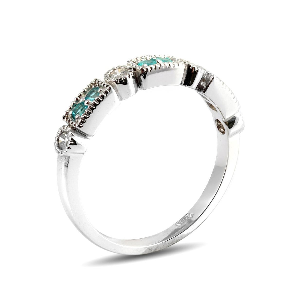 Small yet full of intense teals, here is a band that showcases 0.13 carats of Paraiba Tourmalines. Each gem set in 14K White Gold prongs, and paired with diamonds that add an illuminating light, this is a ring that comes alive thanks to its vibrant