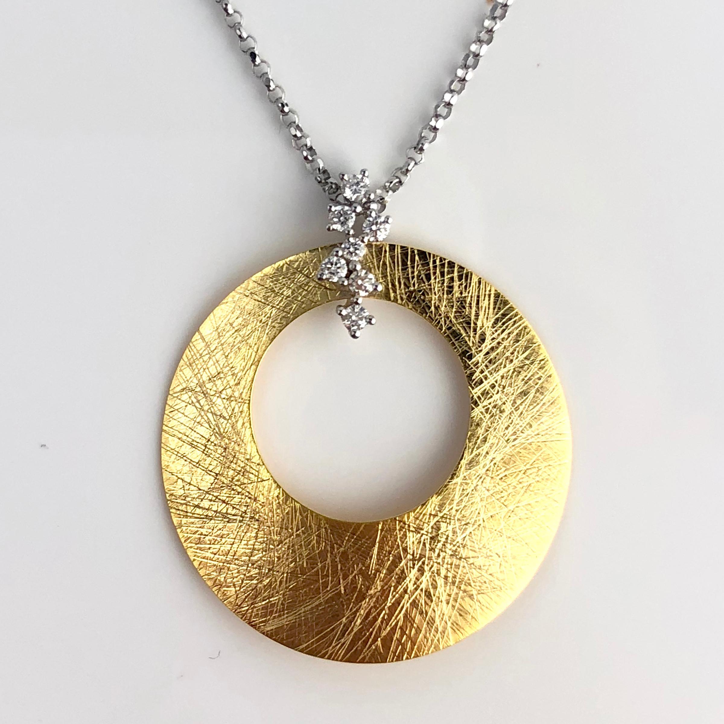 (DiamondTown) This pendant is a round disc with round cutout, accented by a 0.14 carat diamond branch design. A gorgeous accompaniment to any occasion.

Set in 14k Yellow and White Gold.

Many of our items have matching companion pieces. Please