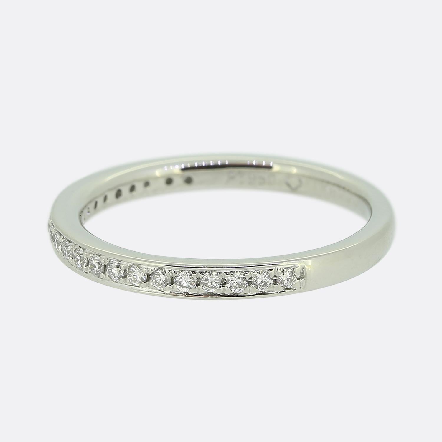 Aquí tenemos un anillo de diamantes medio eternos de platino. Esta esbelta banda está engastada con veintitrés diamantes redondos de talla brillante en una formación de una sola línea; todos ellos han sido engastados individualmente en garras en