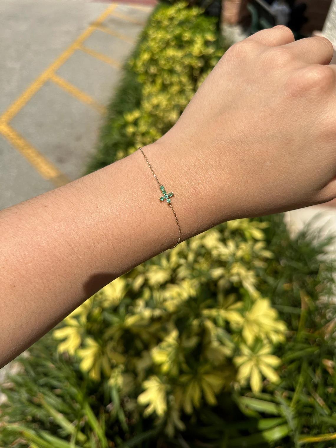 Un bracelet minimaliste en forme de croix d'émeraude. Naturellement, six petites émeraudes rondes d'origine zambienne affichent une belle couleur vert clair-moyen, lustrée et vive. Il est solidement serti et attaché à une chaîne en câble de 1,0 mm