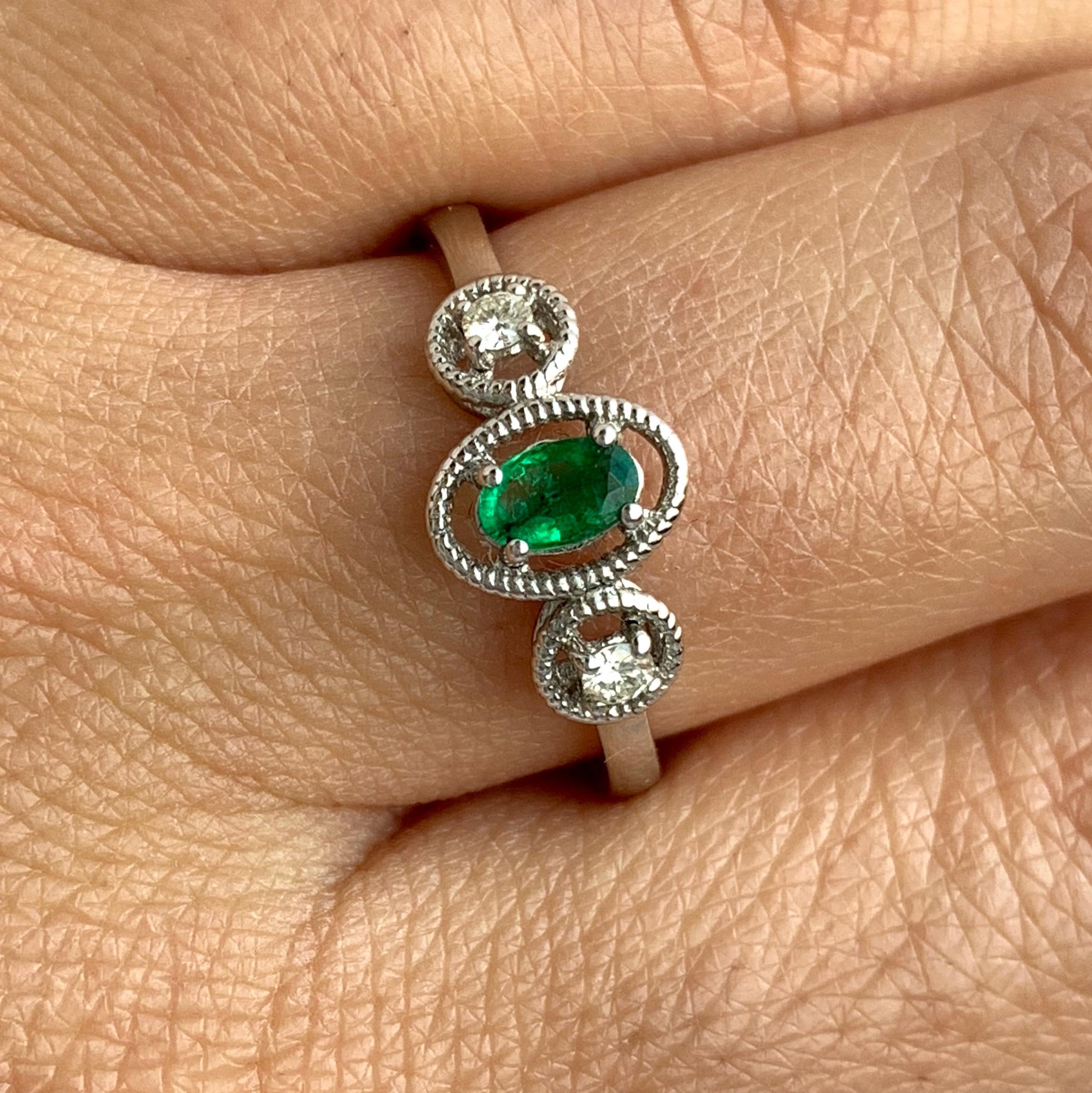 Material: 14k White Gold 
Center Stone Details: 0.21 Carat Oval Emerald measuring 5x 3.3 mm
Mounting Diamond Details: 2 Brilliant Round White Diamonds at 0.07 Carats - Clarity: SI / Color: H-I
Ring Size: Size 6.25 (can be sized)

Fine one-of-a-kind