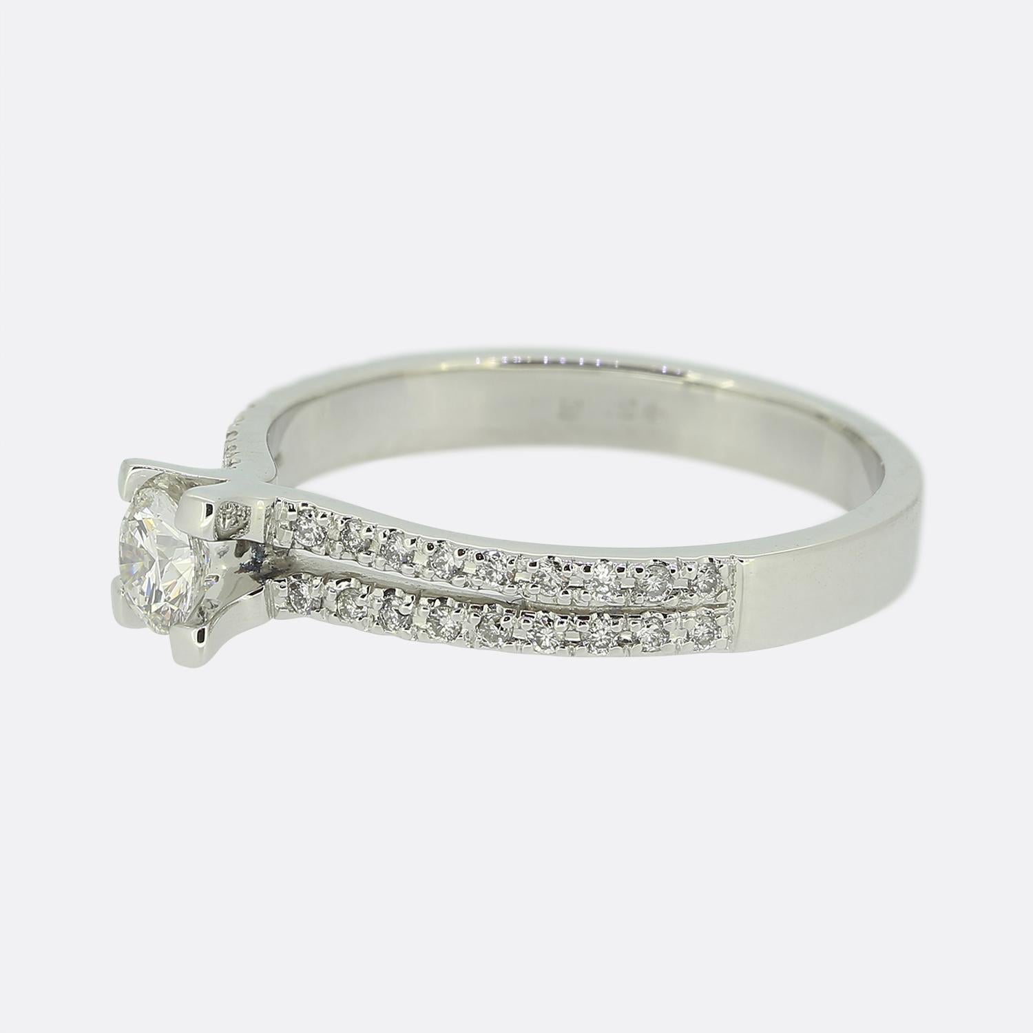 Here we have an 18ct white gold diamond engagement ring. A single round brilliant cut diamond sits alone and proud at the centre of face whilst being flanked on either split shoulder by two rows of smaller matching stones before the piece is made