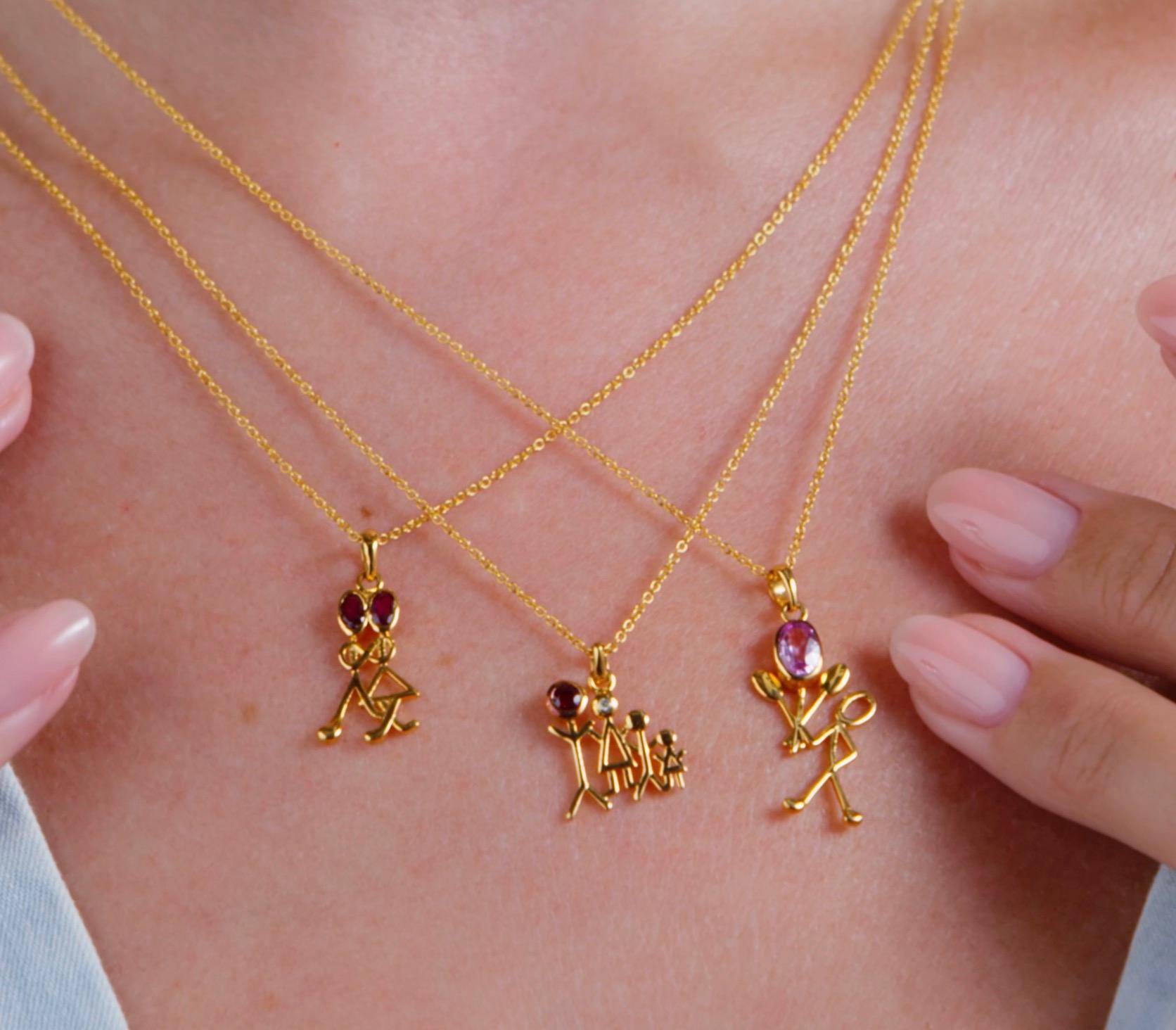 0.24 Carat Ruby Yellow Gold Stick Figure Pendant Necklace (Leftmost in images)

The pendant on this necklace depicts two stick figures (one man and one woman) with ruby heads and holding hands. Their arms form an infinity symbol. This necklace is