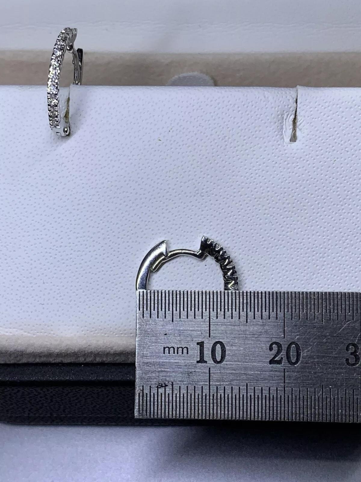 These stunning 0.24ct diamond hoop huggie earrings are made of 18ct white gold and weigh 2.1g. The elegant design features a classic hoop with a huggie closure, perfect for everyday wear. The earrings are adorned with sparkling white diamonds that
