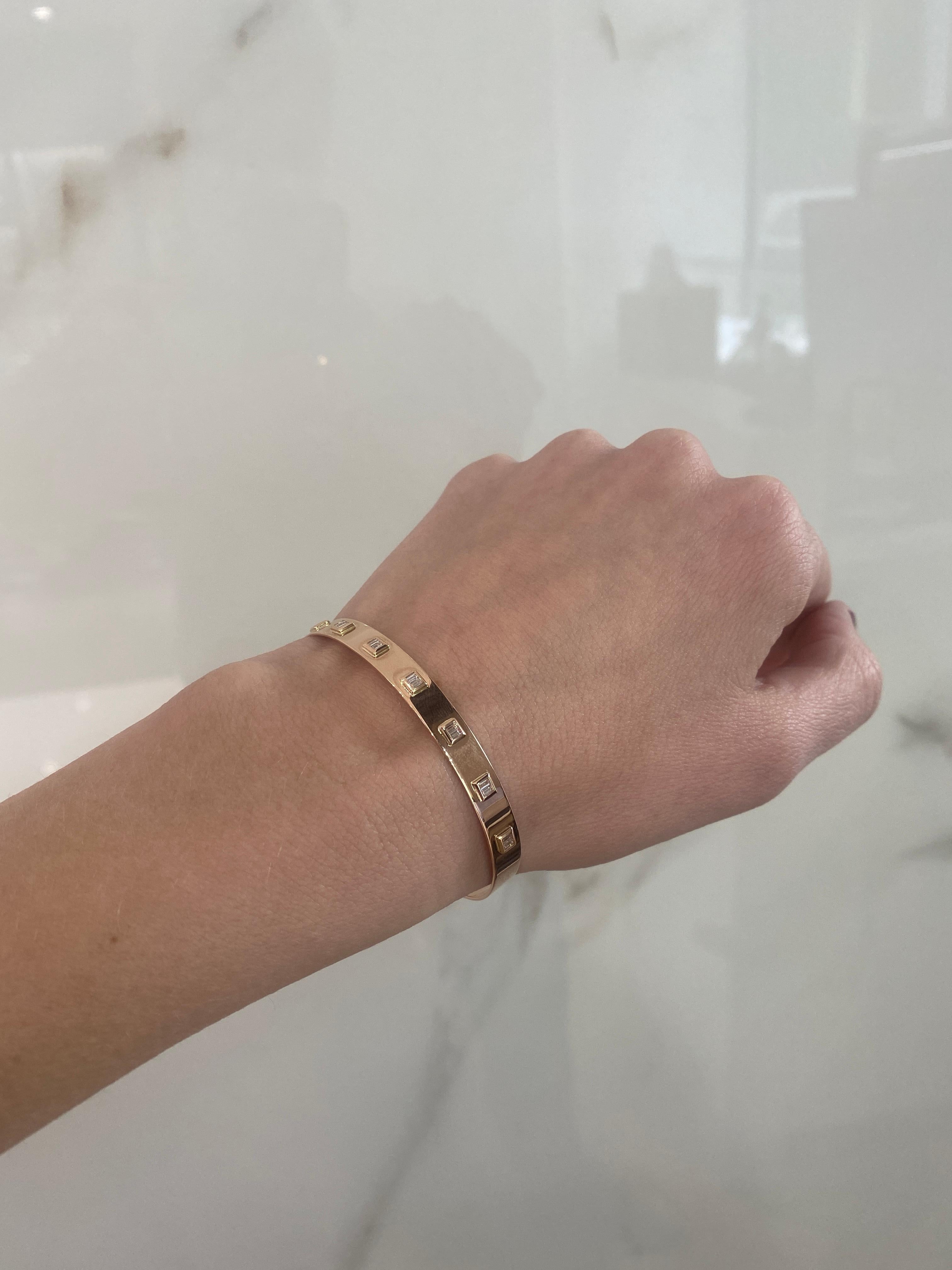 A modern bangle featuring 0.24 carat total weight in 14 bezel set diamonds, SI2-I1 j-k, set in 14 karat rose gold. This bracelet has an adjustable closure and can fit up to 6.25