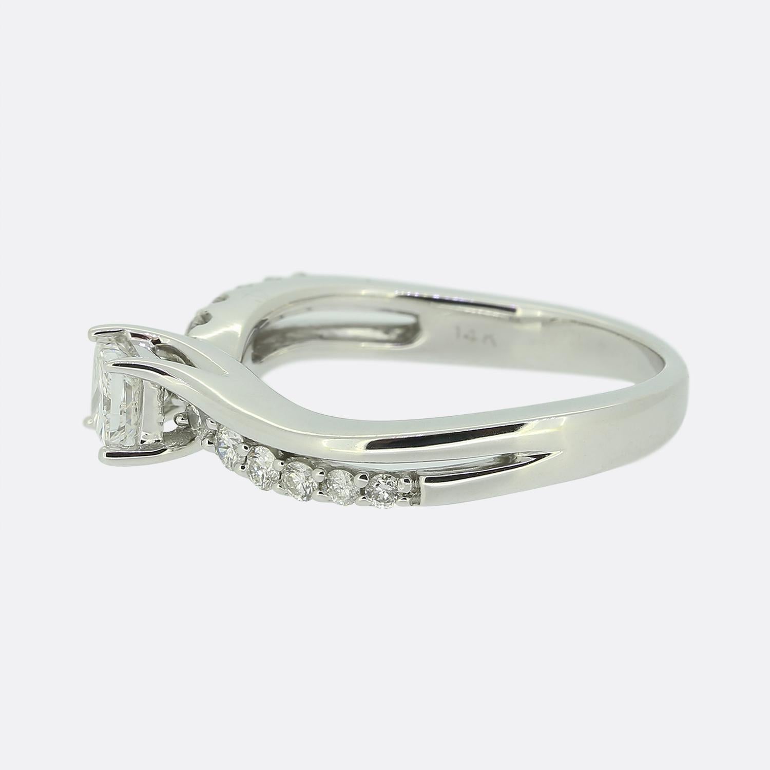 Hier haben wir einen diamantenen Solitärring aus 14 Karat Weißgold. Der zentrale Diamant im Prinzessinnenschliff wiegt 0,25 Karat und ist in eine Fassung mit vier Krallen gefasst. Jede gedrehte Schulter ist zusätzlich mit 6 runden Diamanten im