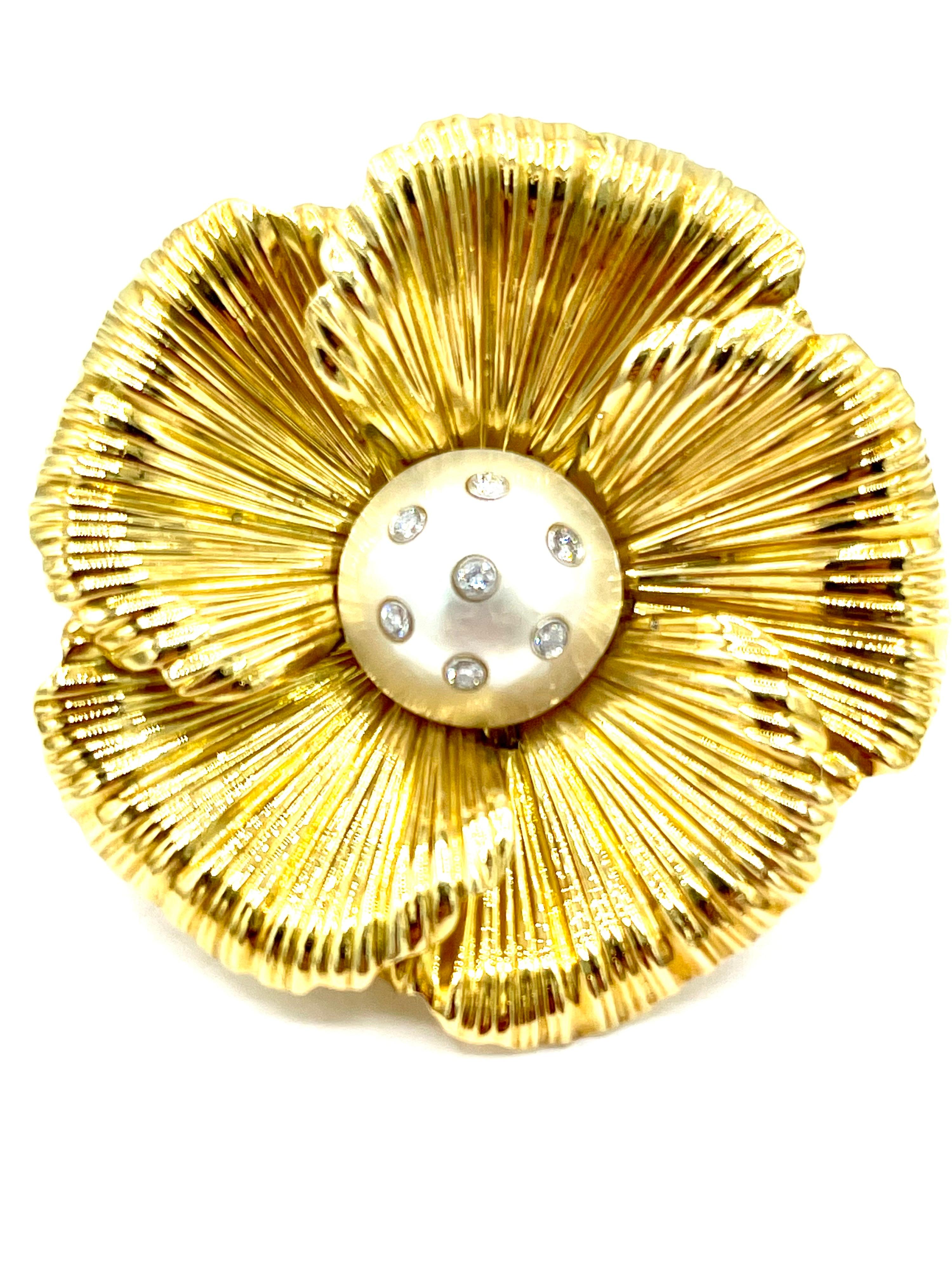 A simple and gorgeous flower brooch.  The brooch has a center Mabe Pearl set with seven round brilliant Diamonds bezel set into the pearl itself.  The petals are made in 18K textured yellow gold with hints of yellow popping through.  The Diamonds