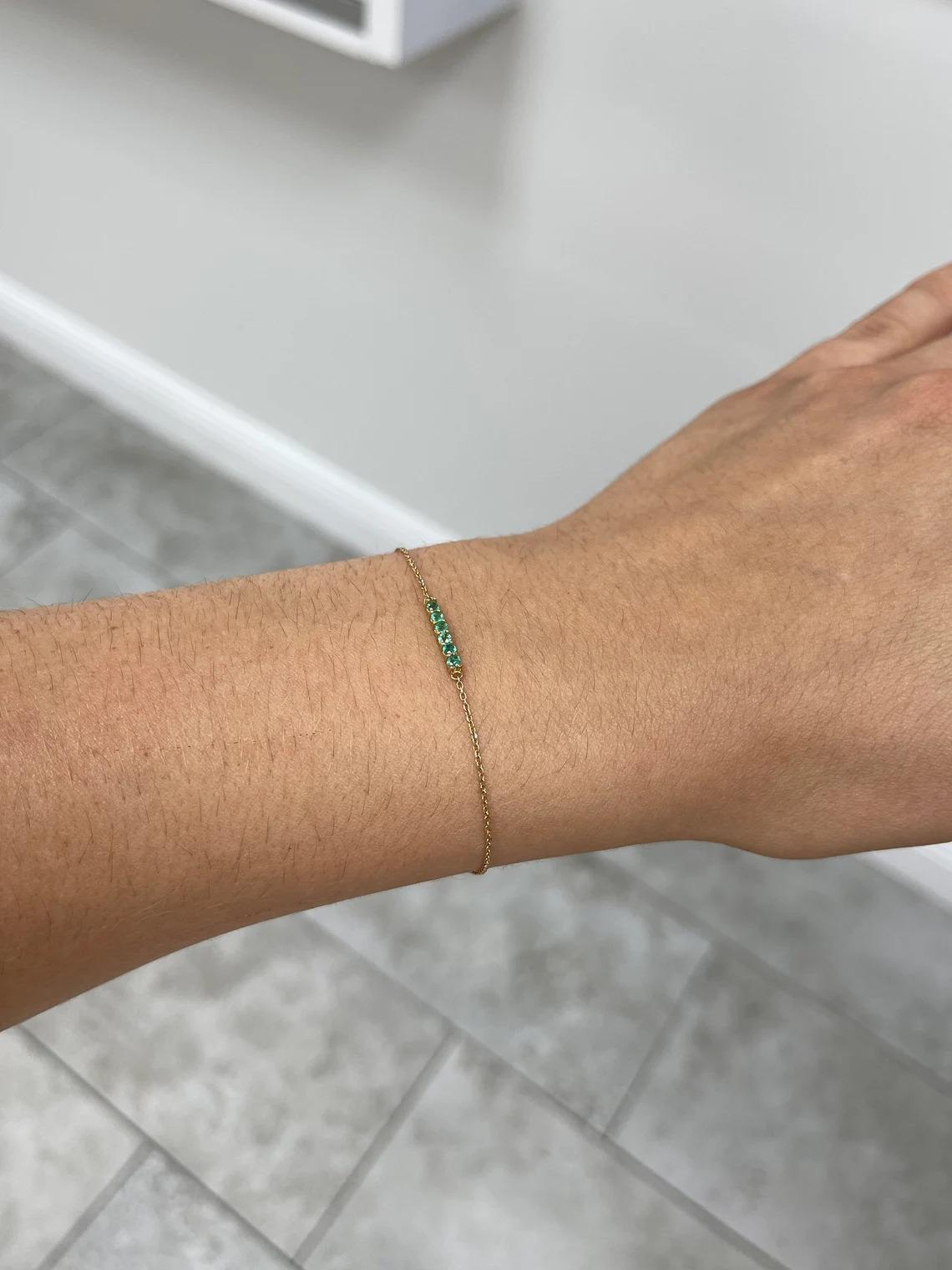 A lovely, simple emerald bracelet. This piece displays six petite round-cut emeralds set in a prong set bar. The gemstones display a gorgeous medium green color with excellent clarity and vividness. Attached to a thin cable chain, that measures 7.5