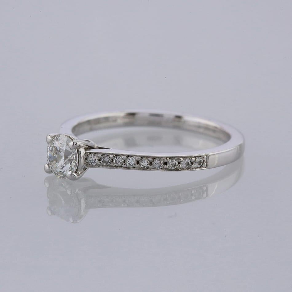Ein Solitärring aus 18 Karat Weißgold mit einem einzelnen runden Diamanten im Brillantschliff in der Mitte und neun kleineren Diamanten auf beiden Seiten.

Zustand: Gebraucht (Ausgezeichnet)
Gewicht: 2.0 Gramm
Größe: M
Diamant-Details: 0,26 Karat,