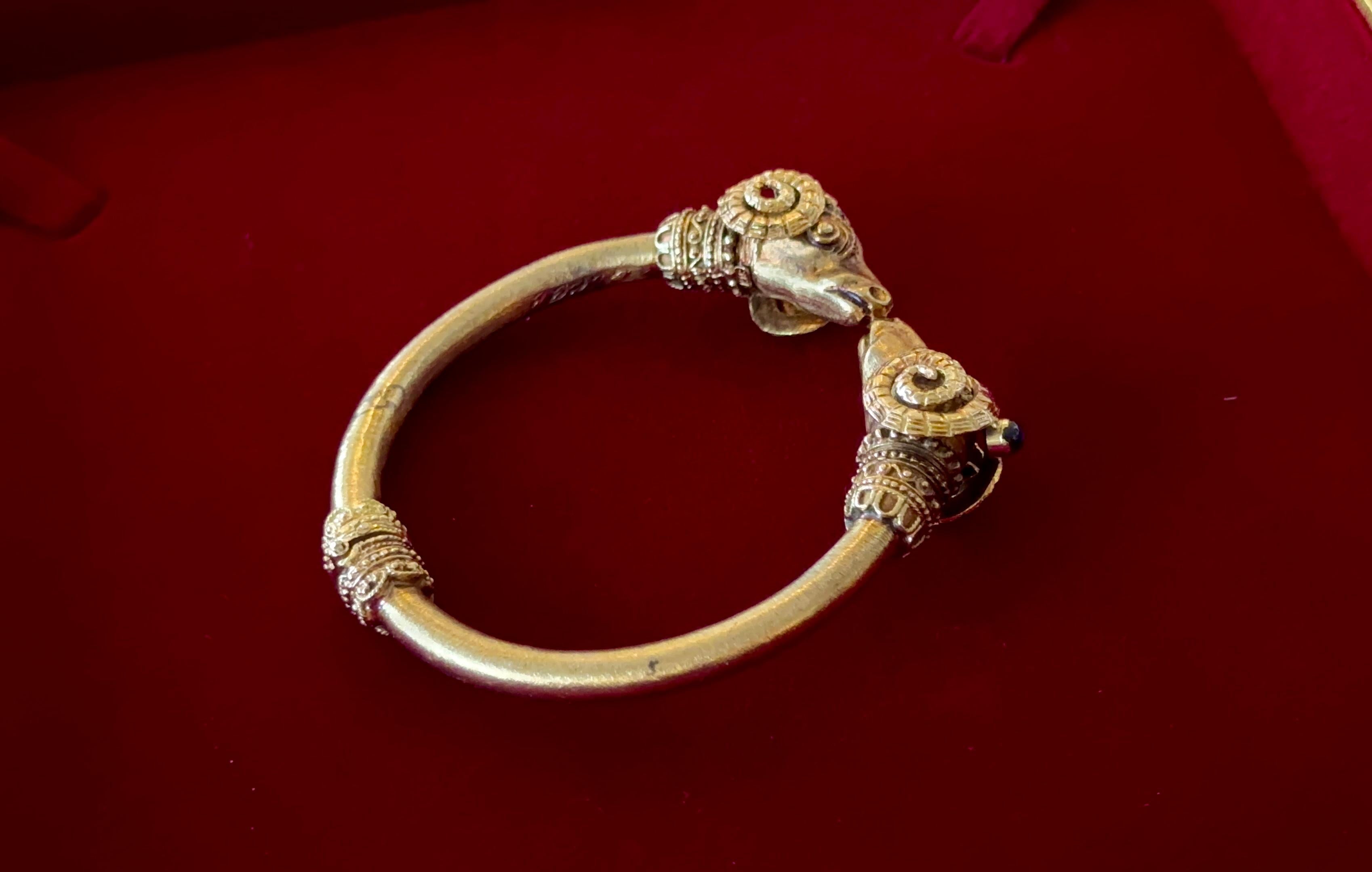 Vintage 18K Yellow Gold Etruscan Double Ram's Head Bracelet Cuff with Natural blue spphire.
Métal : or massif 18 carats.
Poids de l'or : 50,75 grammes.
Pierre précieuse : Saphir bleu naturel.
Poids de la pierre : environ 0,30 ctw.

