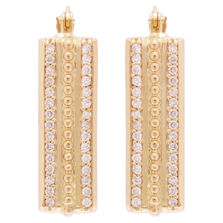 Los aros son geniales, ¡pero los aros cuadrados son aún mejores! Pequeñas cuentas de oro y no una, sino dos filas de diamantes hacen de estos aros un pendiente imprescindible en tu colección de pendientes. Es la mezcla perfecta de ostentación y