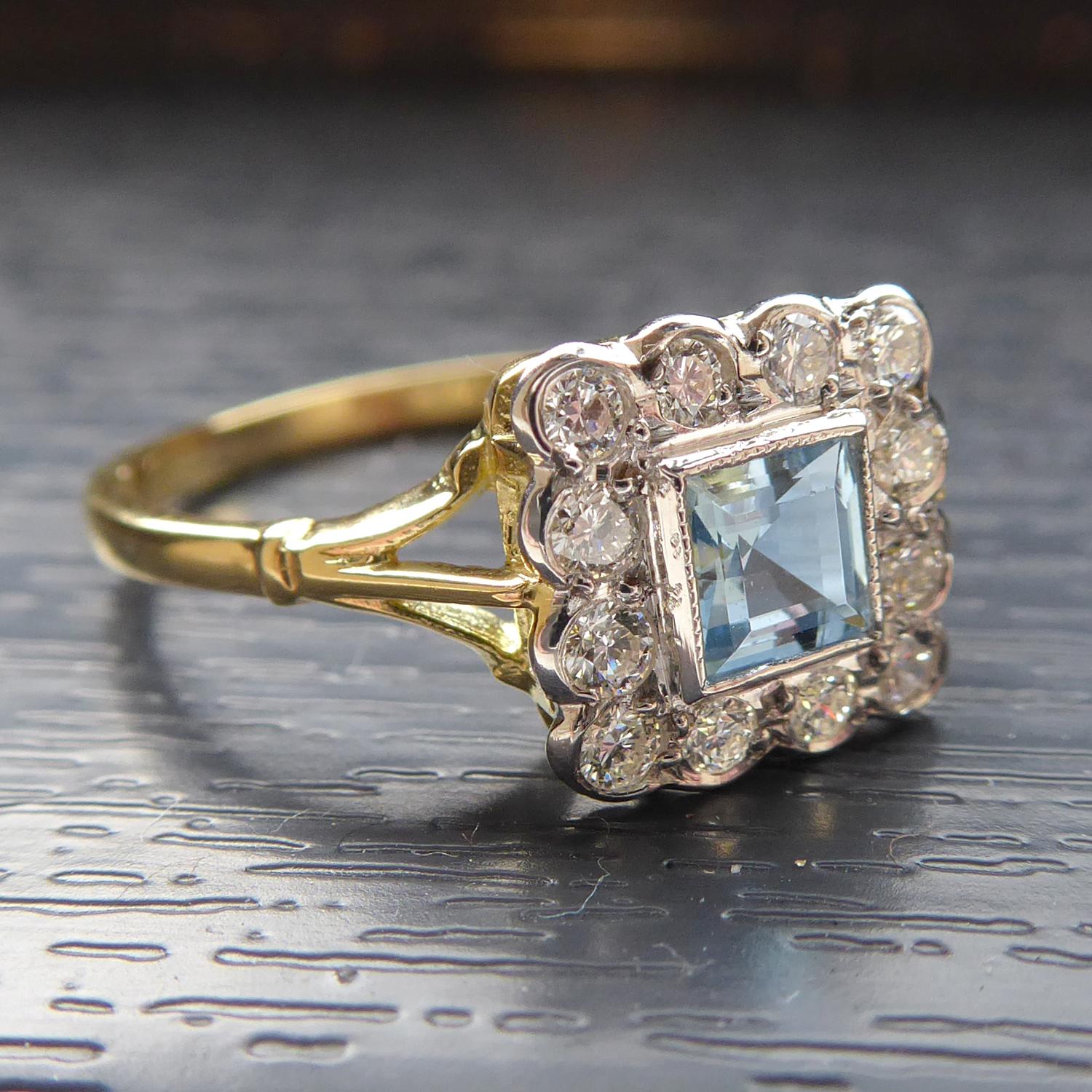 A classic and elegant aquamarine and diamond cluster ring in an Art Deco style that remains popular today.  Set to the centre with a square, step cut emerald 0.30ct in a white rub-over, millegrain edged setting.  A surround of 12 round brilliant cut