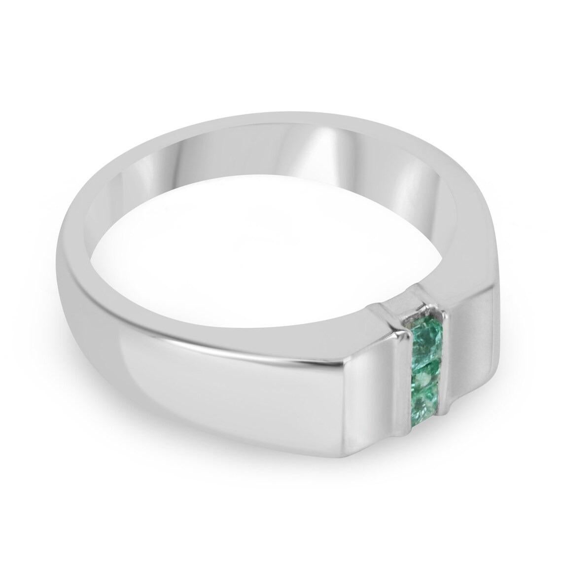 A dapper three-stone natural emerald men's ring that features three Asscher cut emeralds in the very center channel set north to south. The gemstones showcase a lovely medium green color with excellent-very good clarity and luster. Crafted in