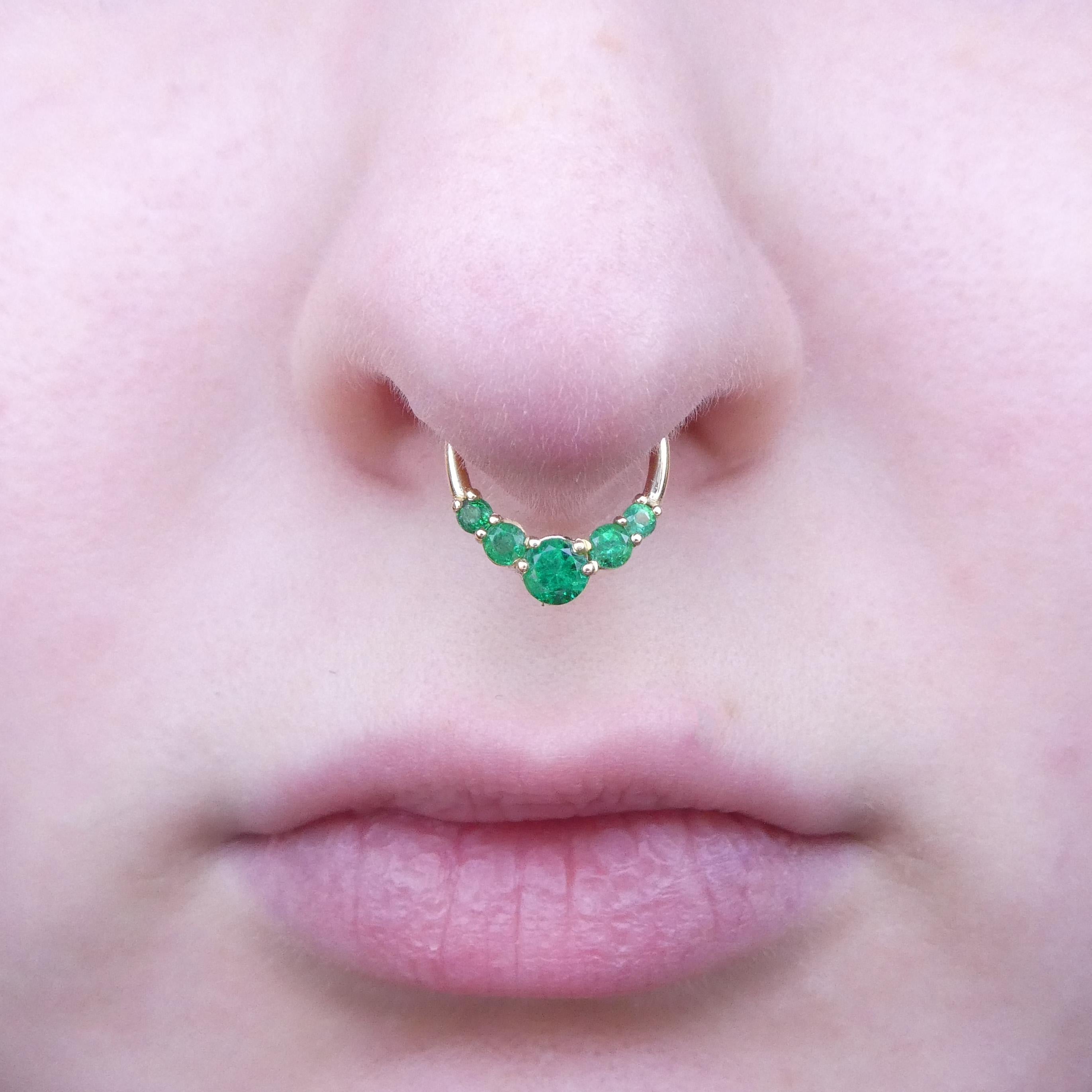 Diameter: 10mm
Thickness: 1.20 mm (16 Gauge)


Introducing our enchanting 0.32ct Round Green Emerald Hinged Septum Clicker Hoop, a striking fusion of elegance and individuality. Crafted with precision and set in lustrous 14k yellow gold, this septum