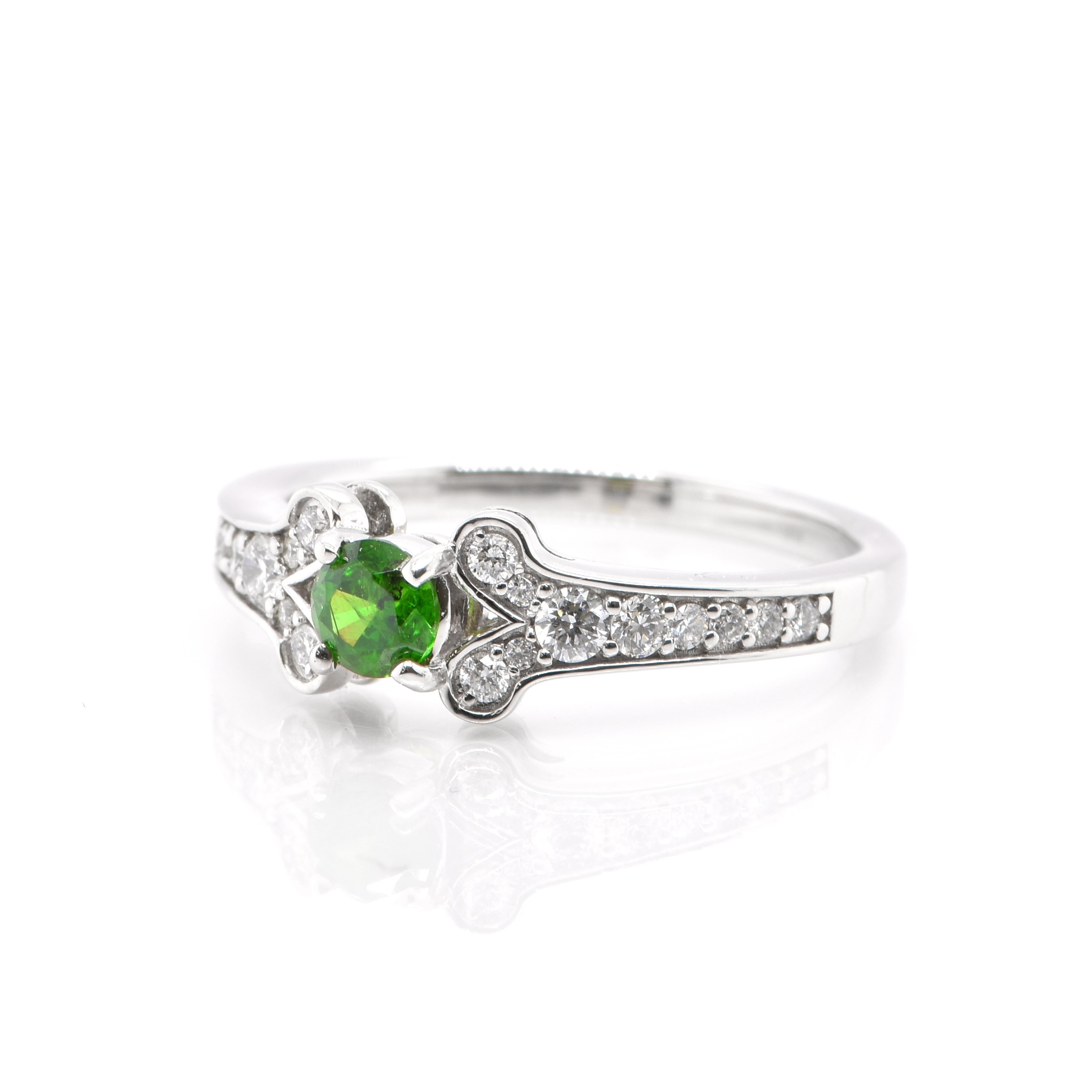 A beautiful Engagement ring consisting of a 0.33 Carat, Natural Demantoid Garnet and 0.26 Carats of White Round Brilliant Diamond Accents. Demantoid Garnet's only known source used to be the Ural Mountains in Russia however recent discoveries in