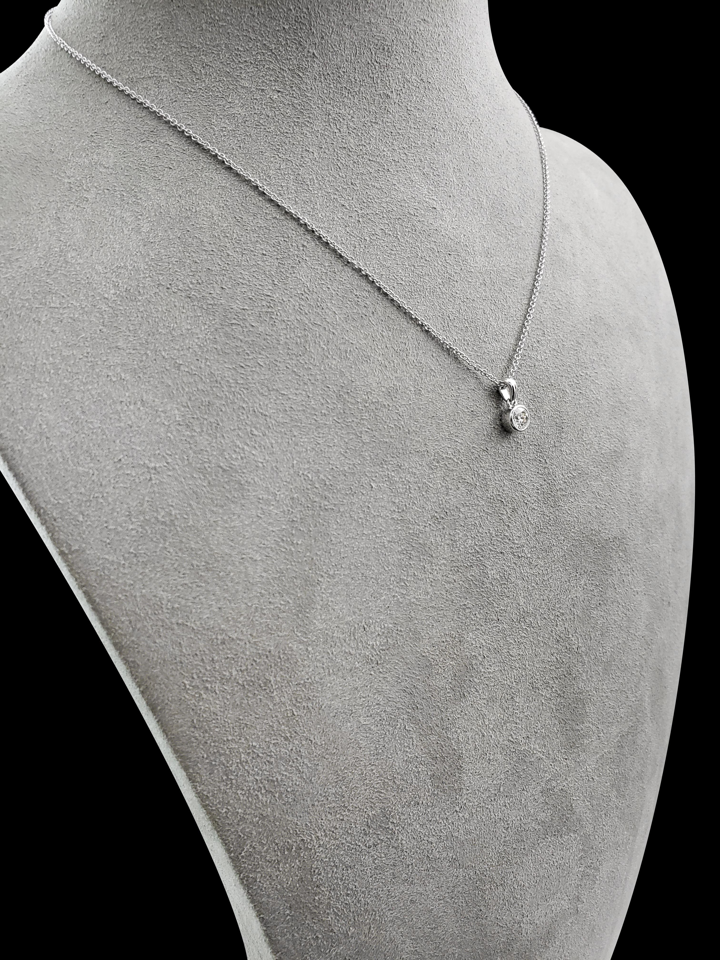 A unique pendant necklace showcasing a 0.34 carat round diamond set on an 18 karat white gold bezel. Suspended on a rounded bale; attached to an 18 inch white gold chain. 

Style available in different price ranges. Prices are based on your