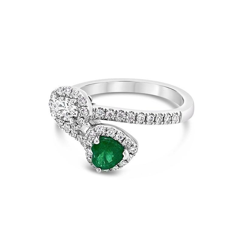 This unique ring features a 0.35 carat heart shaped emerald and a 0.19 carat oval cut diamond accented with 0.38 carat total weight in round diamonds set in 14 karat white gold. This ring is currently a size 6.