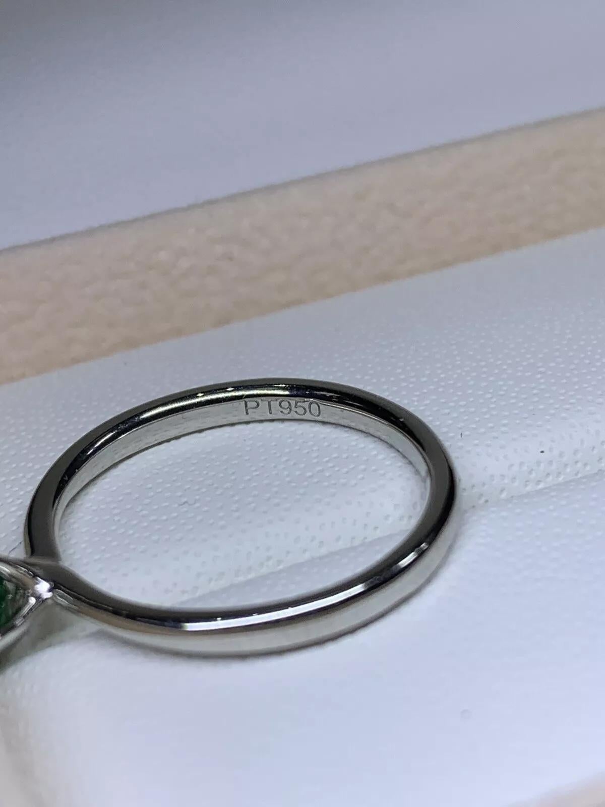 Cette bague de fiançailles solitaire magnifiquement travaillée est ornée d'une superbe émeraude colombienne comme pierre principale, sertie dans un platine de haute qualité. Cette bague est parfaite pour toute occasion spéciale, qu'il s'agisse de