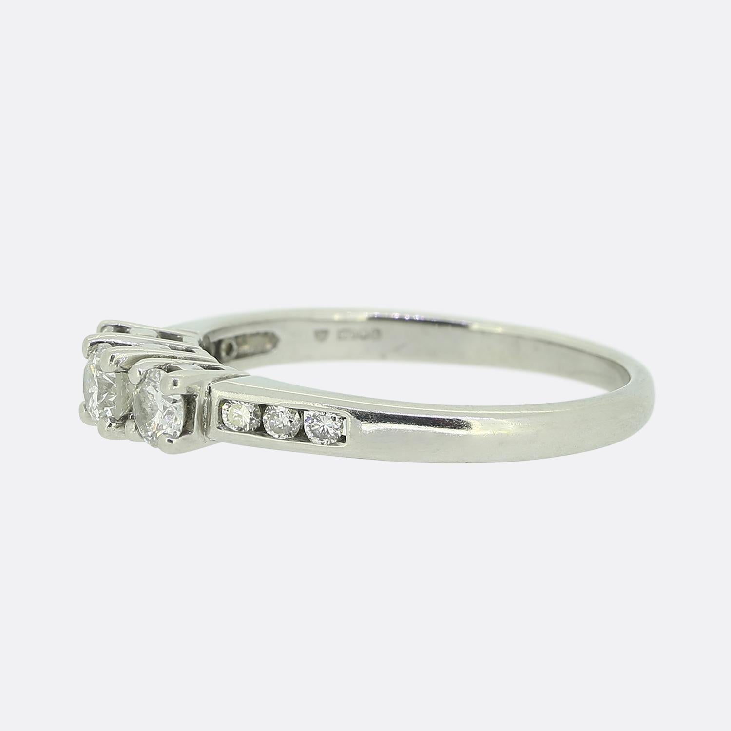 Ecco un anello di platino con tre pietre e diamanti. Un trio di accattivanti diamanti rotondi taglio brillante sono stati incastonati singolarmente al centro del viso, mentre tre piccole pietre abbinate scendono su entrambe le spalle in