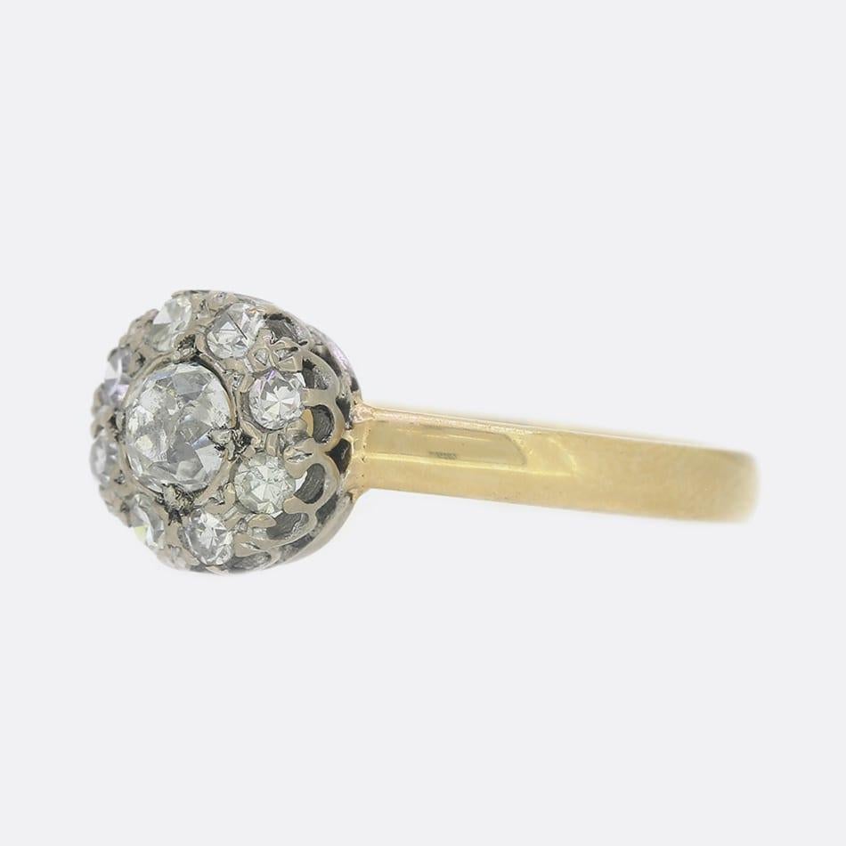 This is an 18ct yellow gold diamond daisy cluster ring. The ring plays host to a central old cut diamond which has been claw set and surrounded by a further 8 old cut diamonds with a yellow gold shank. This ring has been converted from a vintage