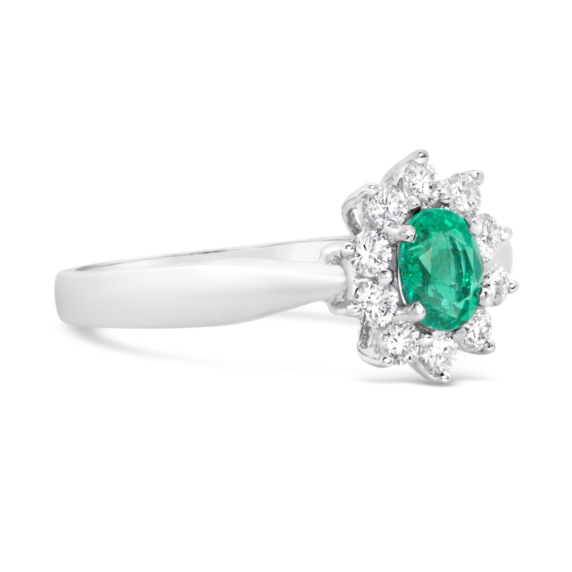 Uno splendido anello di fidanzamento con uno smeraldo ovale da 0,40 carati, incastonato su quattro punte arrotondate. Accentuato da un'aureola di 10 diamanti rotondi taglio brillante per un peso totale di 0,28 carati, incastonati con un motivo