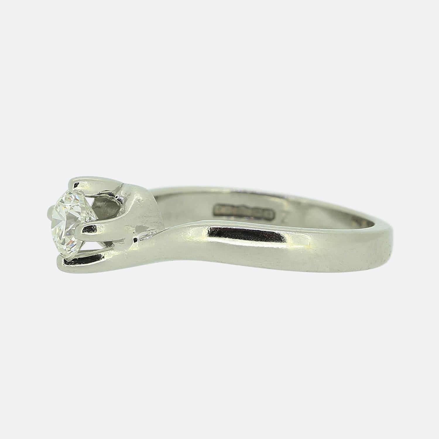 Hier haben wir einen diamantenen Verlobungsring aus Platin. Im Mittelpunkt dieses Schmuckstücks steht ein runder Diamant im Brillantschliff von 0,40 Karat, der stolz in der Mitte des Zifferblatts in einer Vierkrallenfassung sitzt, die in der Mitte