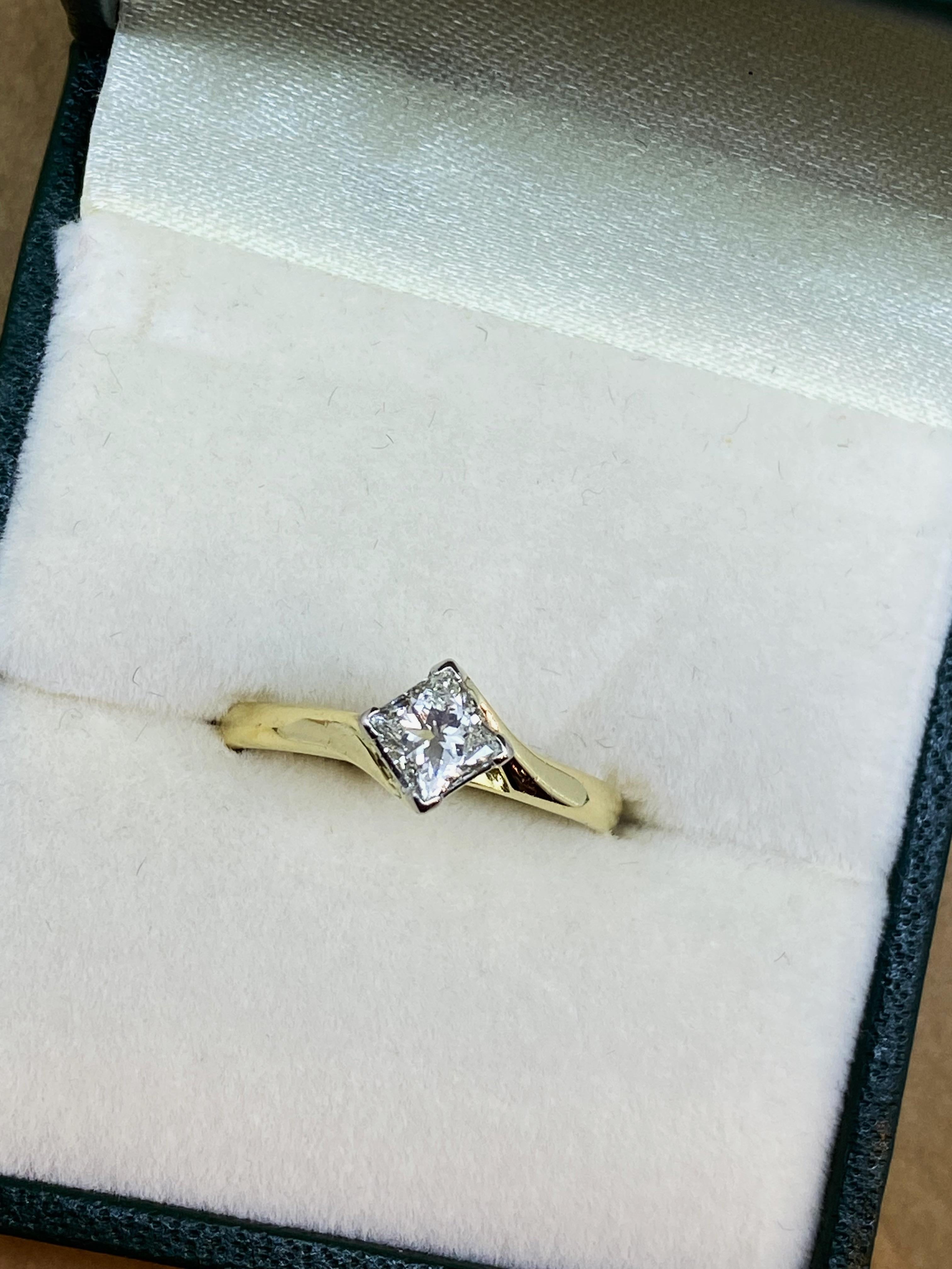 Serti à quatre griffes avec un diamant de taille princesse étincelant 
de 0,40ct environ (5mm)
de couleur H, clarté VS 
dans un cadre élégant de dérivation,
dépassant le doigt de 6 mm 

Finement réalisé en or jaune 18 carats 

La tige est arrondie
