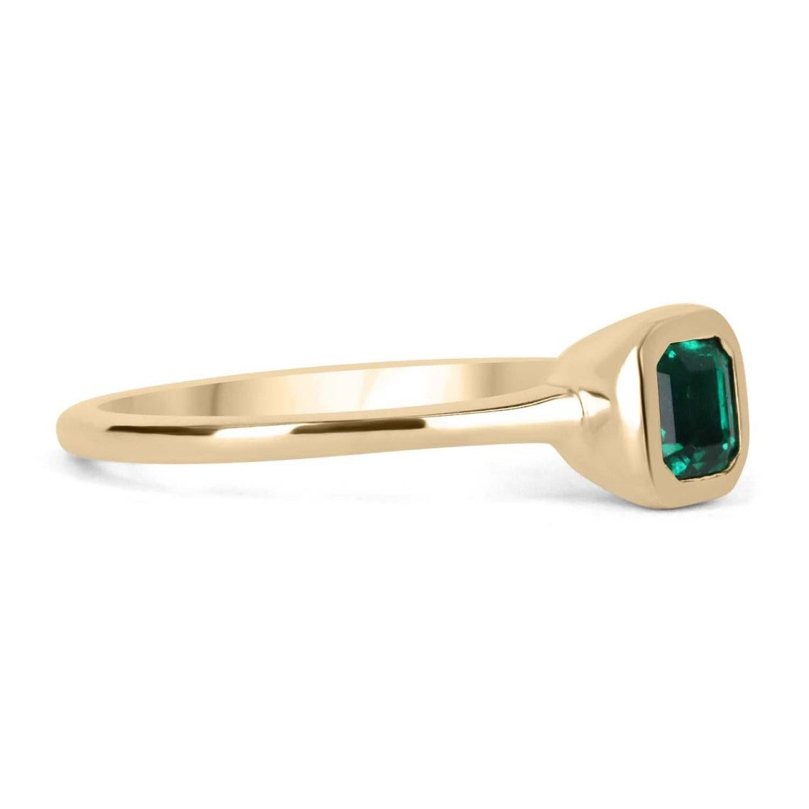 Displayed is a bespoke Colombian emerald solitaire emerald-cut engagement/right-hand ring in 18K yellow gold. This gorgeous solitaire ring carries an Asscher cut emerald in a bezel setting. Fully faceted, this gemstone showcases excellent shine. The