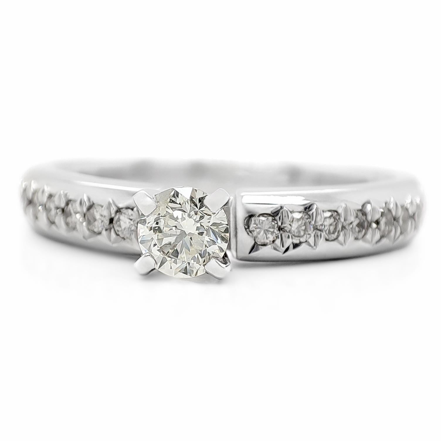 FOR US CUSTOMER NO VAT!

 The central diamond in this elegant ring weighs 0.26 carats and has a light yellow color making it a unique and charming choice.

Adding to its allure, the ring is adorned with 14 smaller round diamond stones, totaling 0.15