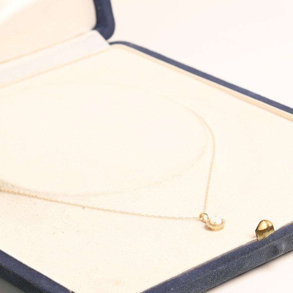 This exquisite necklace showcases a mesmerizing Australian opal at its center, held securely in an elegant prong setting. The opal’s captivating play of colors is further enhanced by a halo of brilliant, meticulously arranged diamonds, creating a