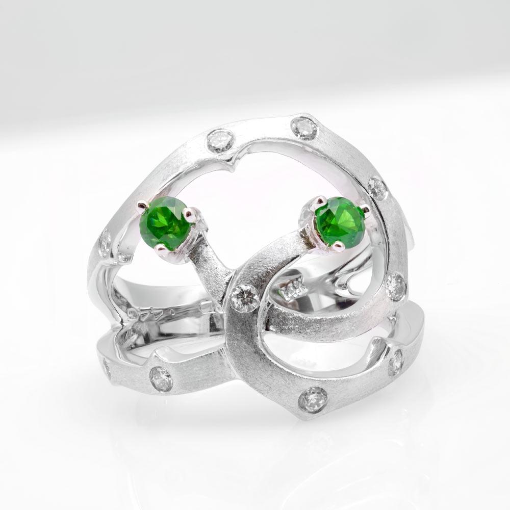 Demantoid garnets have an electric green with a rich fire that beams from the gemstone. This ring that comes set with two round demantoids that have been mined in Russia add to the sensual curves of this 14K white gold ring. Paired with natural