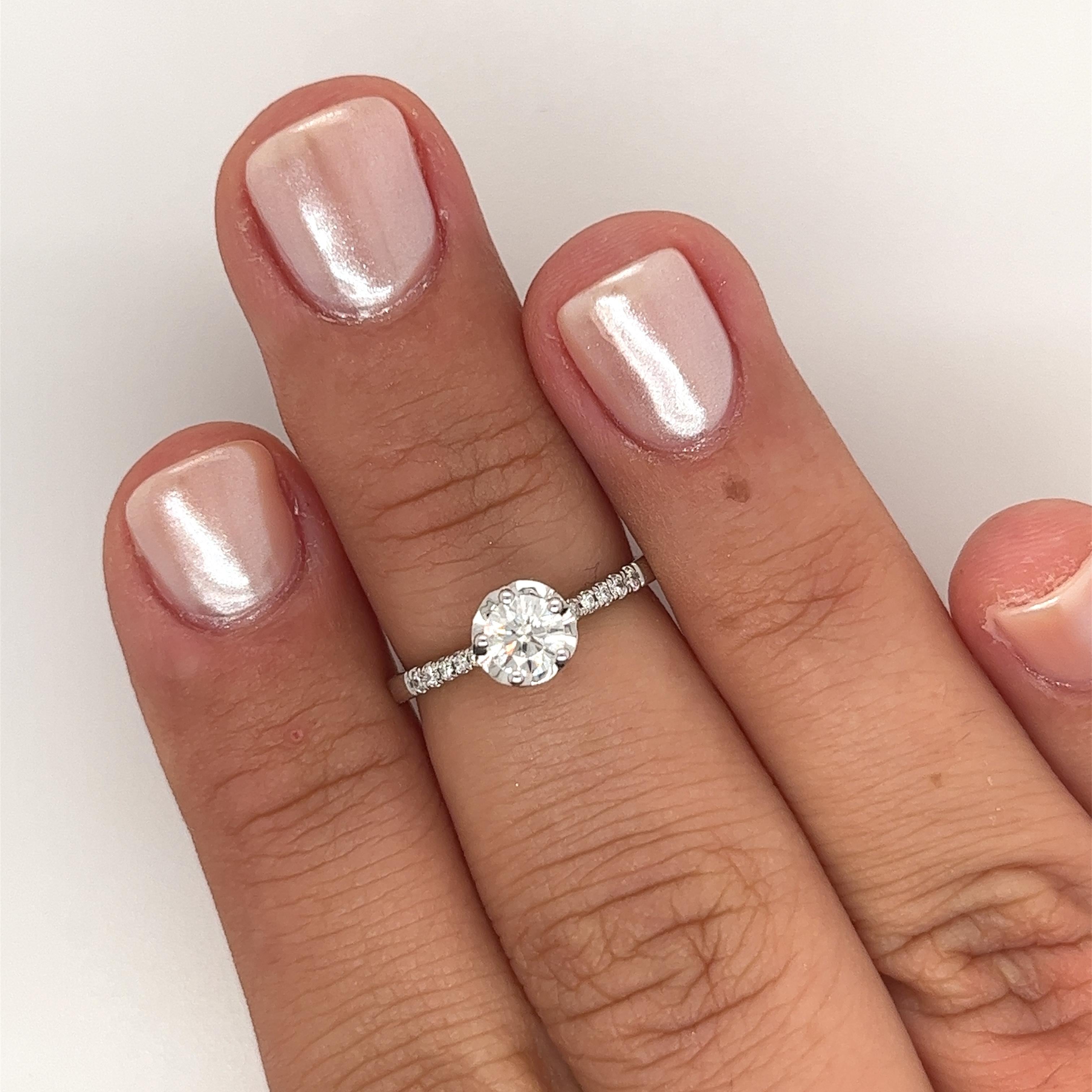 18K White Gold Engagement Ring. The centerpiece is a captivating 0.38 Carat Round Cut Diamond with an H color and VS2 clarity. The ring's elegant design features 10 additional Round Cut Diamonds on the side, totaling 0.06 Carats. Weighing 2.11 grams