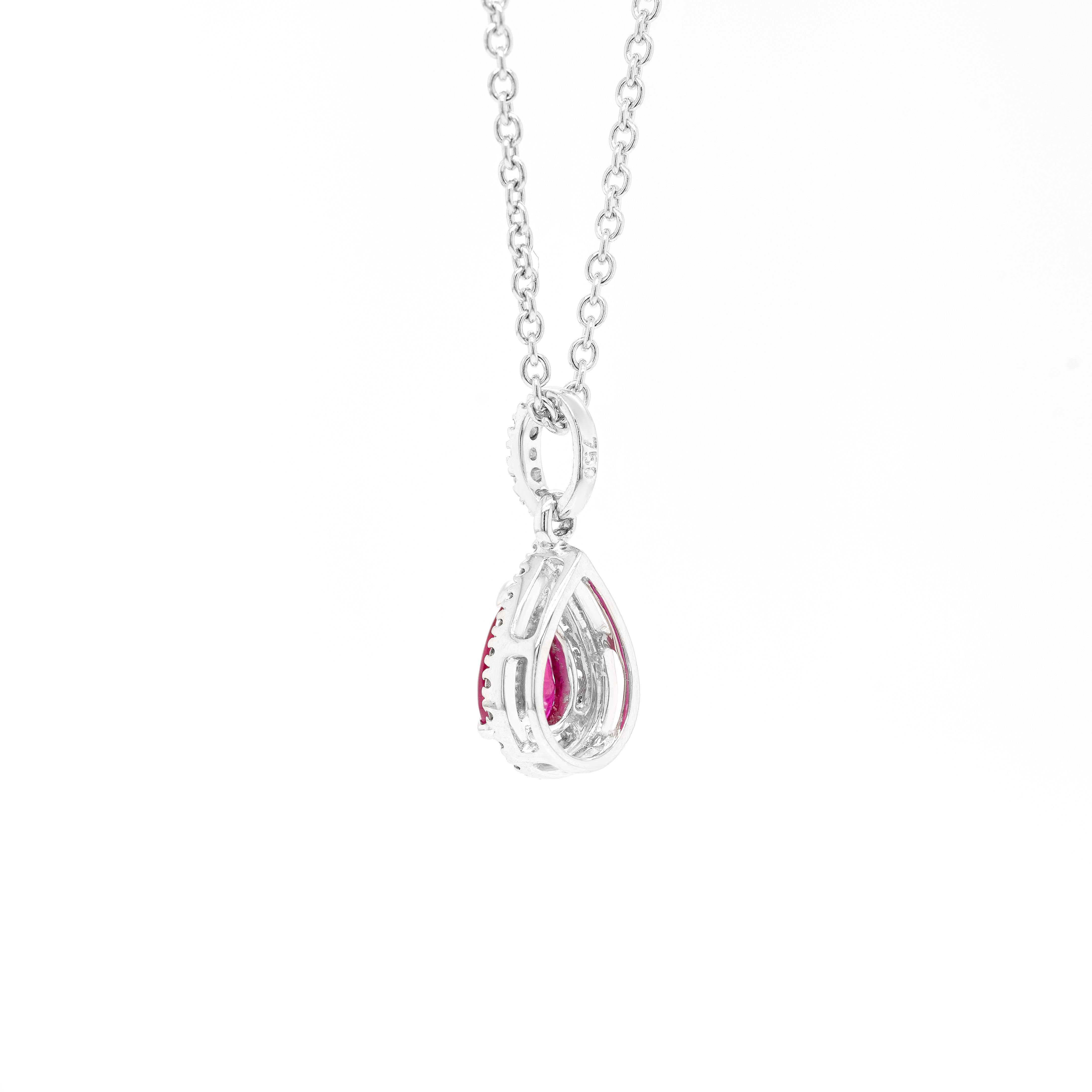 This exquisite 18 carat white gold pendant features a wonderful lively red pear shaped ruby weighing 0.45ct, mounted in a three claw, open back setting. The pendant is further designed with a halo set with 19 round brilliant cut diamonds surrounding