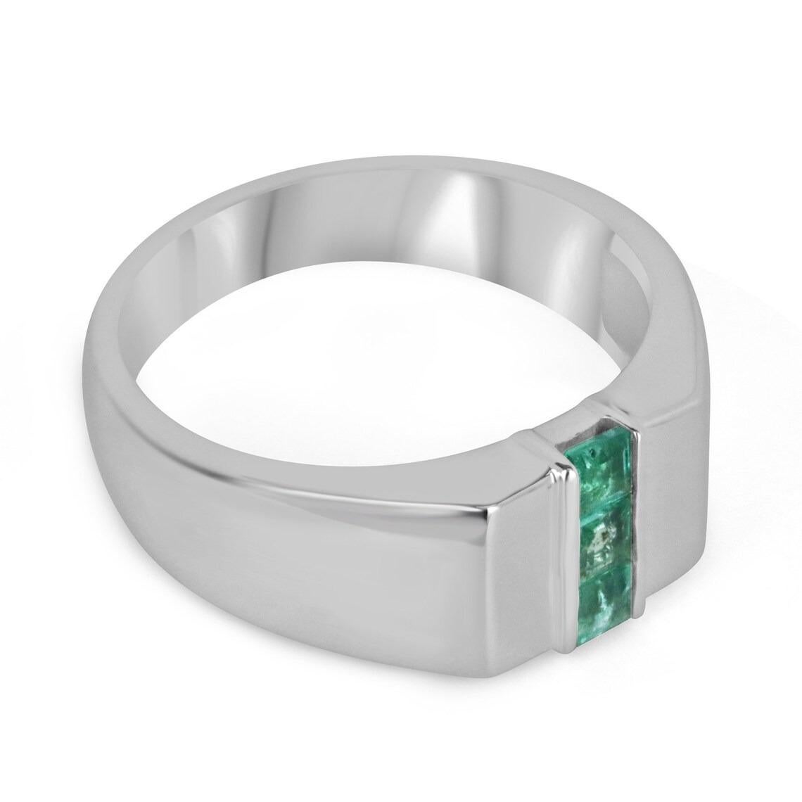 A dapper three-stone natural emerald men's ring that features three Asscher cut emeralds in the very center channel set north to south. The gemstones showcase a lovely medium green color with excellent-very good clarity and luster. Crafted in