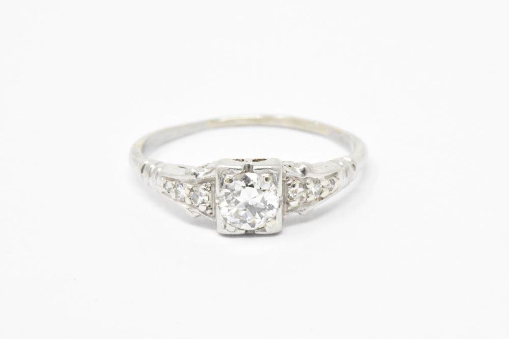 Stunning and bold platinum engagement ring. The center old European cut diamond weighs approximately 0.38 carats, G color and VS clarity. The mounting is decorated in a bold Art Deco style design and is accented by six single cut diamonds weighing
