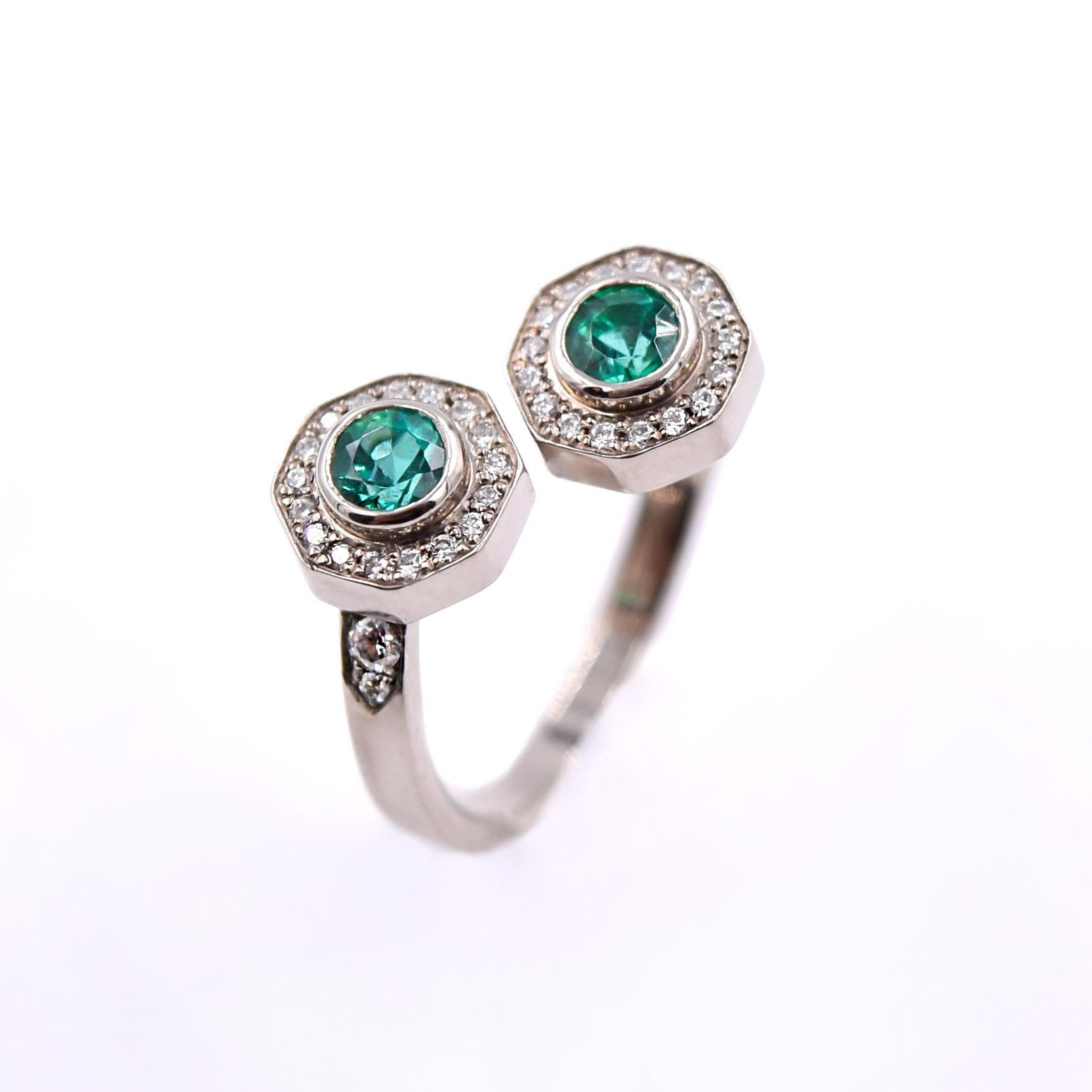 Beautiful bypass diamond ring with two emerald center stones, designed and handcrafted by Lucas Priolo. 

This ring features two round emeralds totaling 0.46 carats, which are carefully set in a bezel setting.
0.38 carats of white diamonds surround