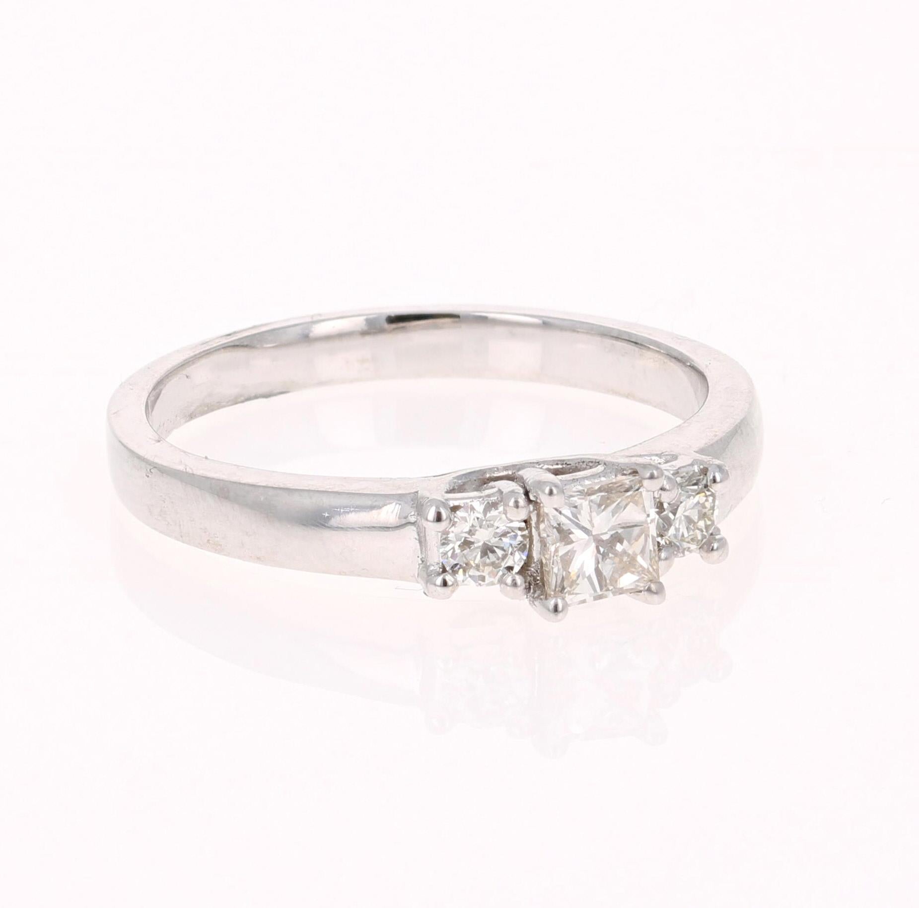 A classic 3-stone Diamond ring set in 18 Karat White Gold.

The center diamond is a Princess Cut Diamond that weighs 0.29 carats (Clarity: VS2, Color: H-I. 
The 2 side diamonds are Round Cut Diamonds that weigh 0.18 carats (Clarity: VS2, Color: