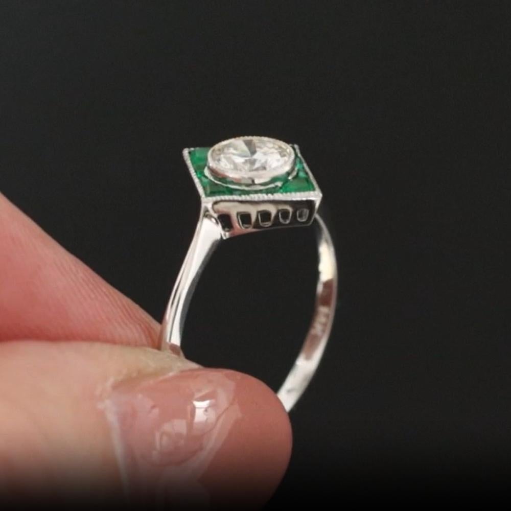 This exquisite cocktail ring features a distinctive geometric target design, showcasing a central 0.47 carat old-cut transictional diamond, encircled by natural emeralds and additional sparkling diamonds, all beautifully set in 14K white gold. The