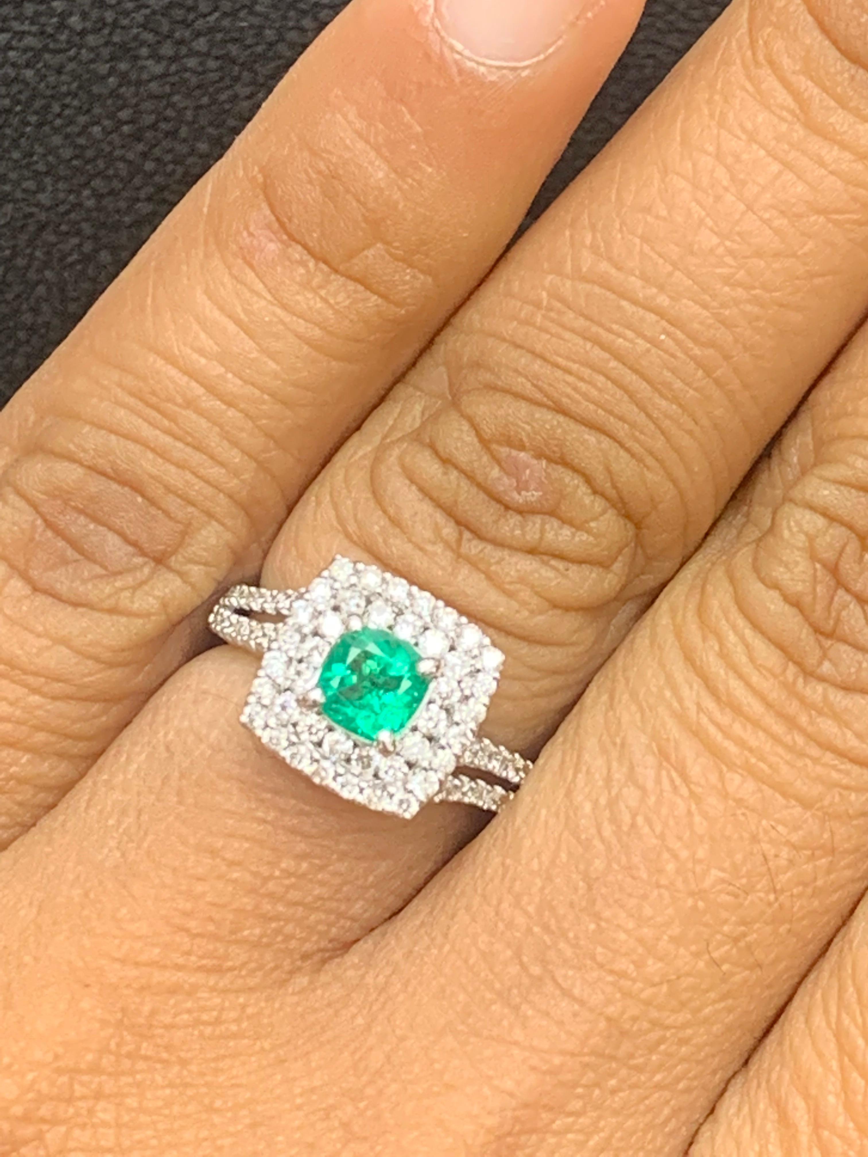 A timeless piece featuring a vibrant cushion-cut emerald weighing 0.48 carats, surrounded by a double row of round brilliant diamonds. Set in a diamond-encrusted double-row shank made in 18k white gold. 76Diamonds weigh 0.61 carats total.