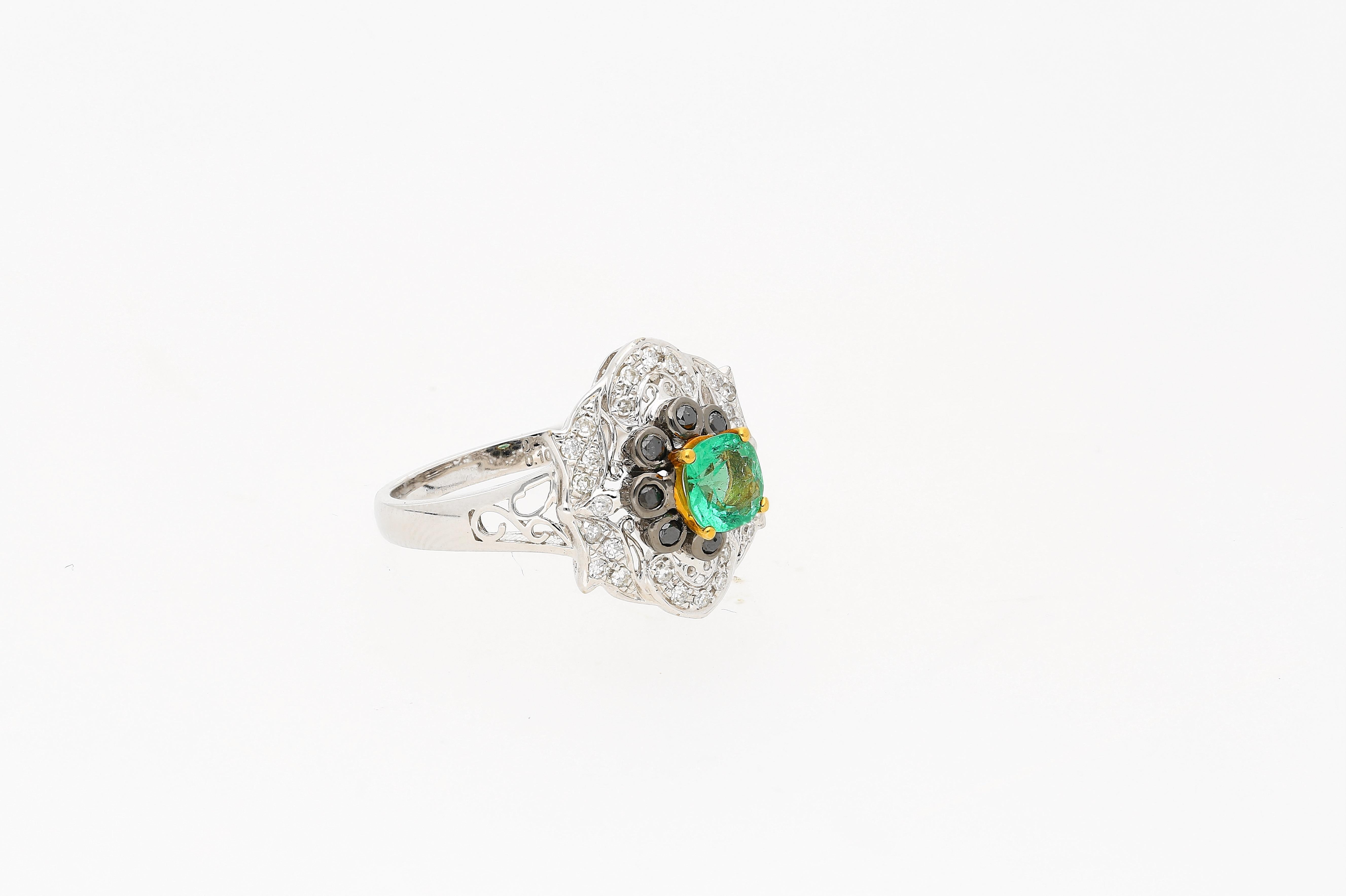 Natural cushion-cut Emerald of 0.48 carats. Center stone Emerald is surrounded by 8 black diamonds of 0.10 carats (total), and 28 round-cut white diamonds of 0.16 carats total. A unique ring with art deco inspirations. 

✔ Gold Karat: 14K 
✔ Emerald