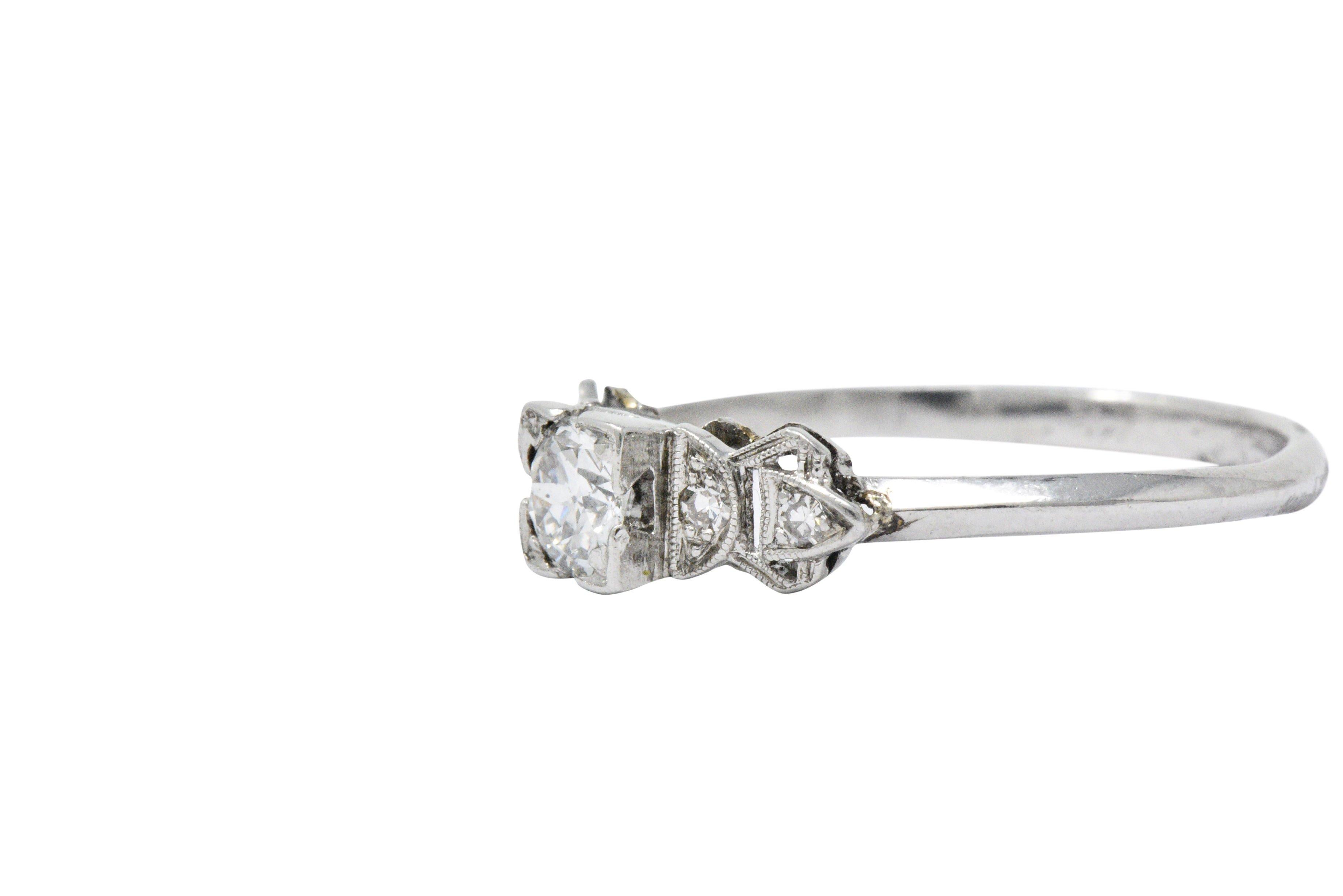 Centering a square form head set with an old European cut diamond weighing approximately 0.40 total; G color and SI clarity

Flanked by pierced triangular shoulders bead set with single cut diamonds weighing approximately 0.08 carat total, eye-clean