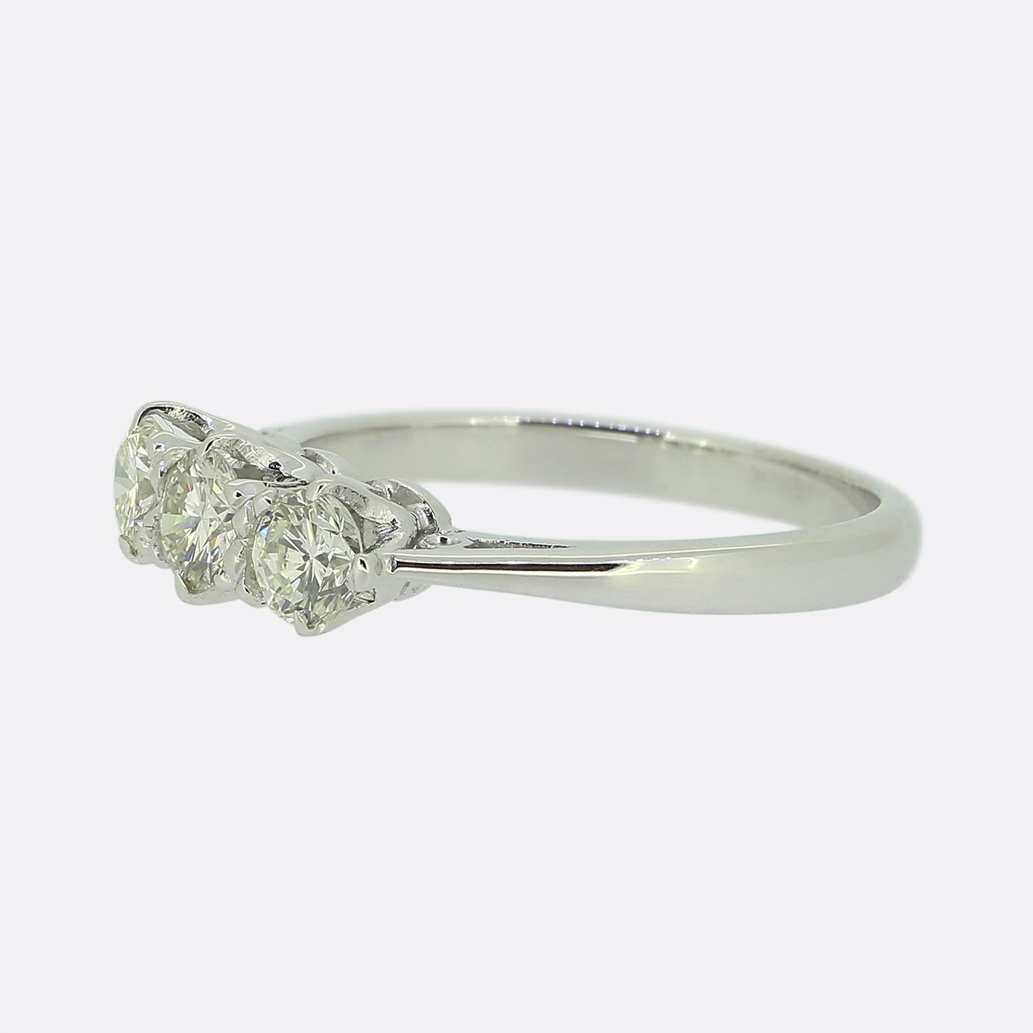 Here we have a classically styled three-stone ring featuring a trio of round brilliant-cut diamonds. Each diamond has been individually claw set in a single line formation to form a harmonious and balanced design. The 18ct white gold band is smooth