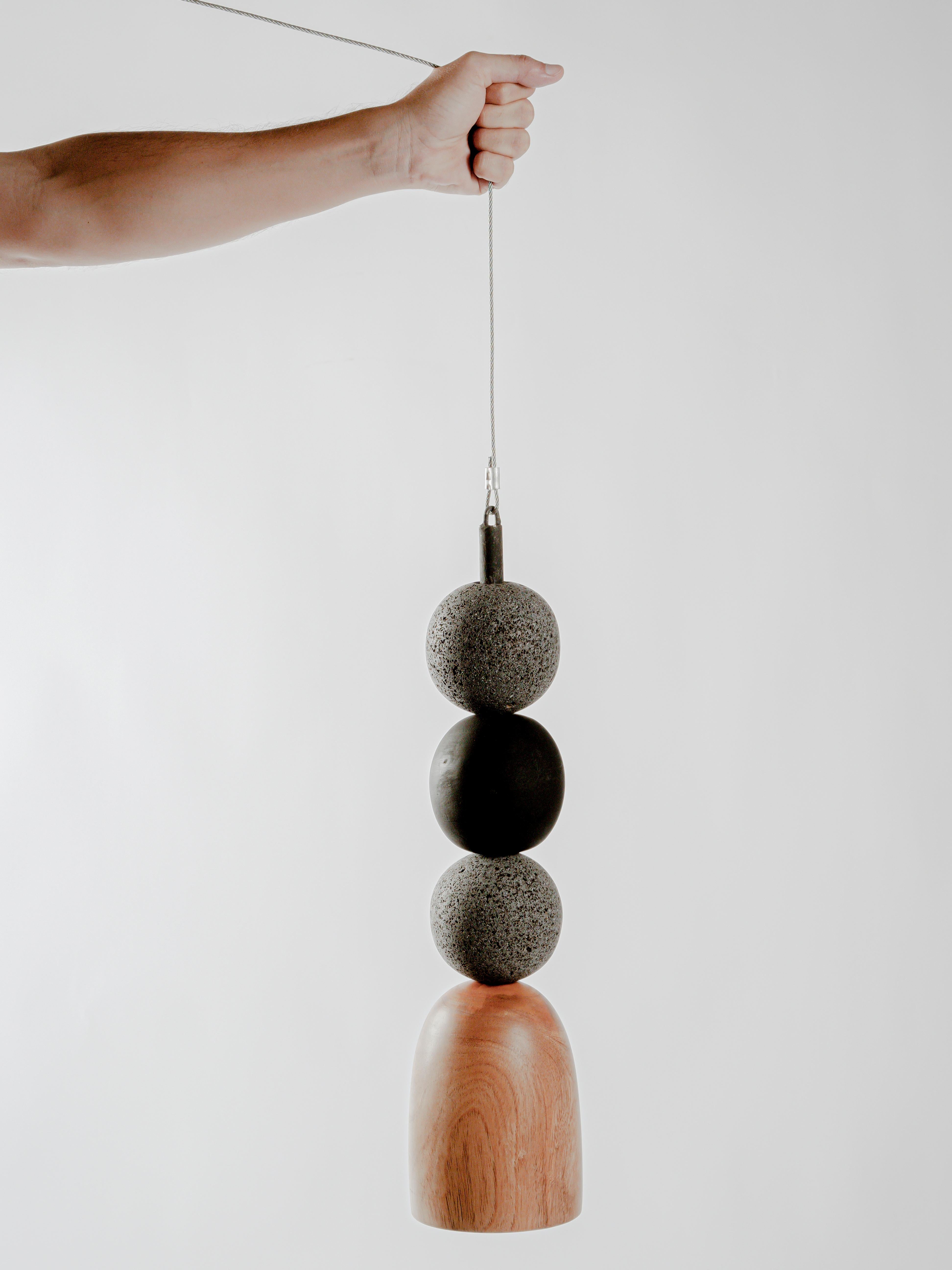05 Lamp by Daniel Orozco
Dimensions: D 13 x H 50 cm.
Materials: Wood, Volcanic Stone

Hanging lamp with natural soap wood and volcanic stone balls and burned wood. Handmade by Mexican artisans.

All our lamps can be wired according to each country.
